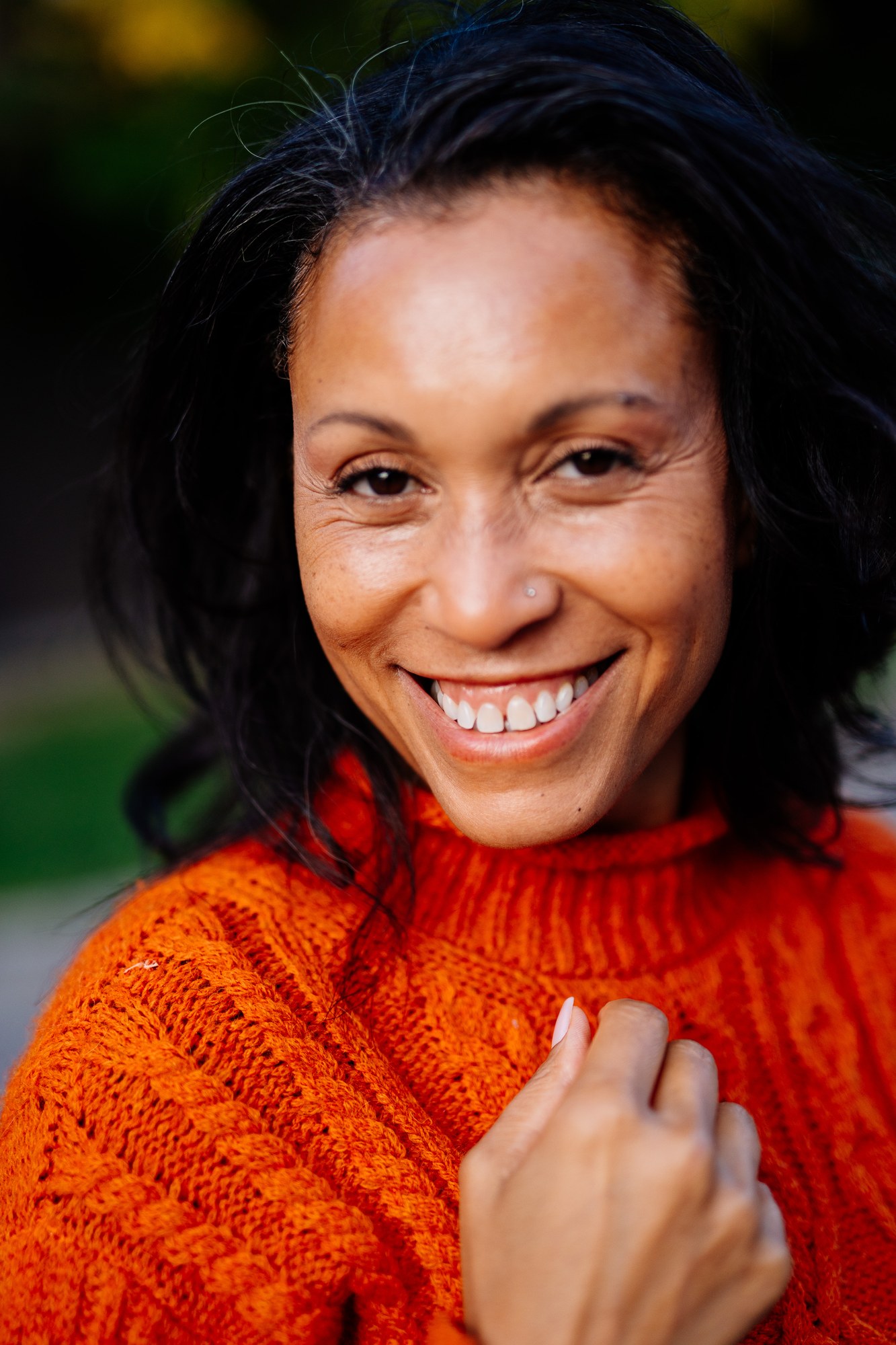 Rebekah smiling at the camera in an orange knit sweater