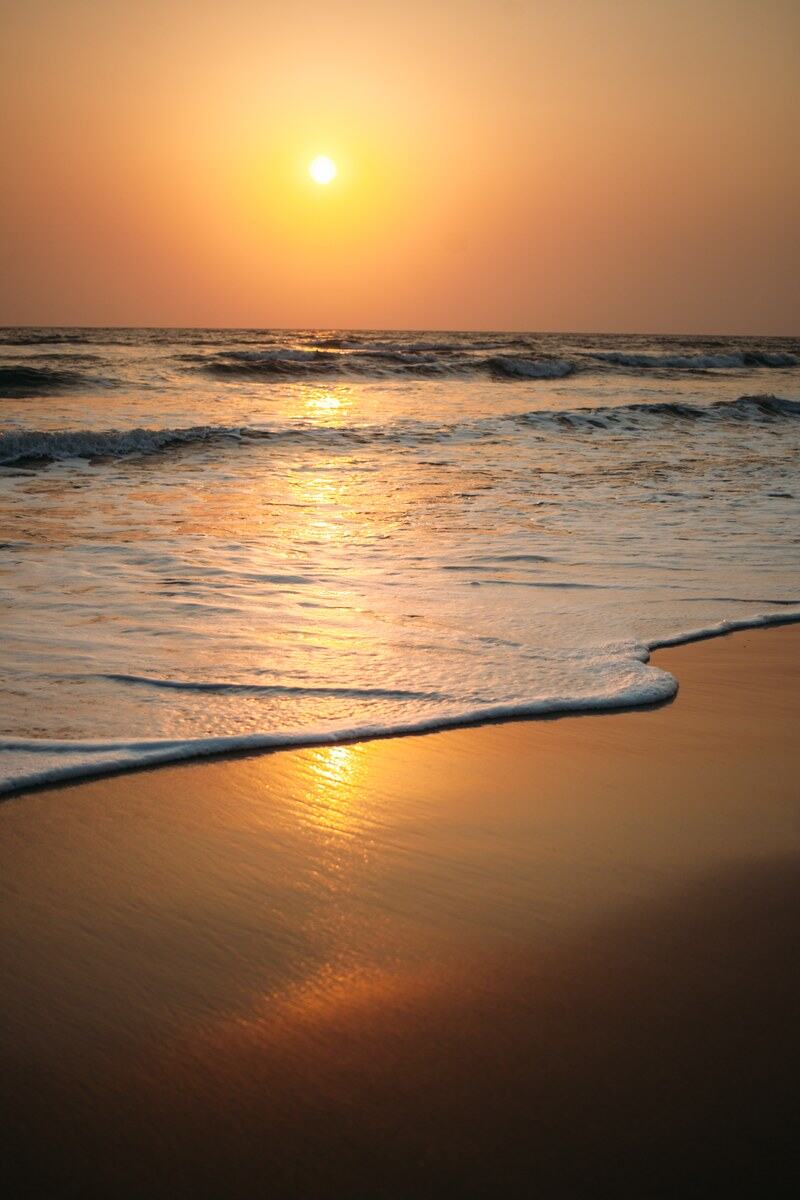 Foam curls up a Goa beach in warm sunset light. print option
