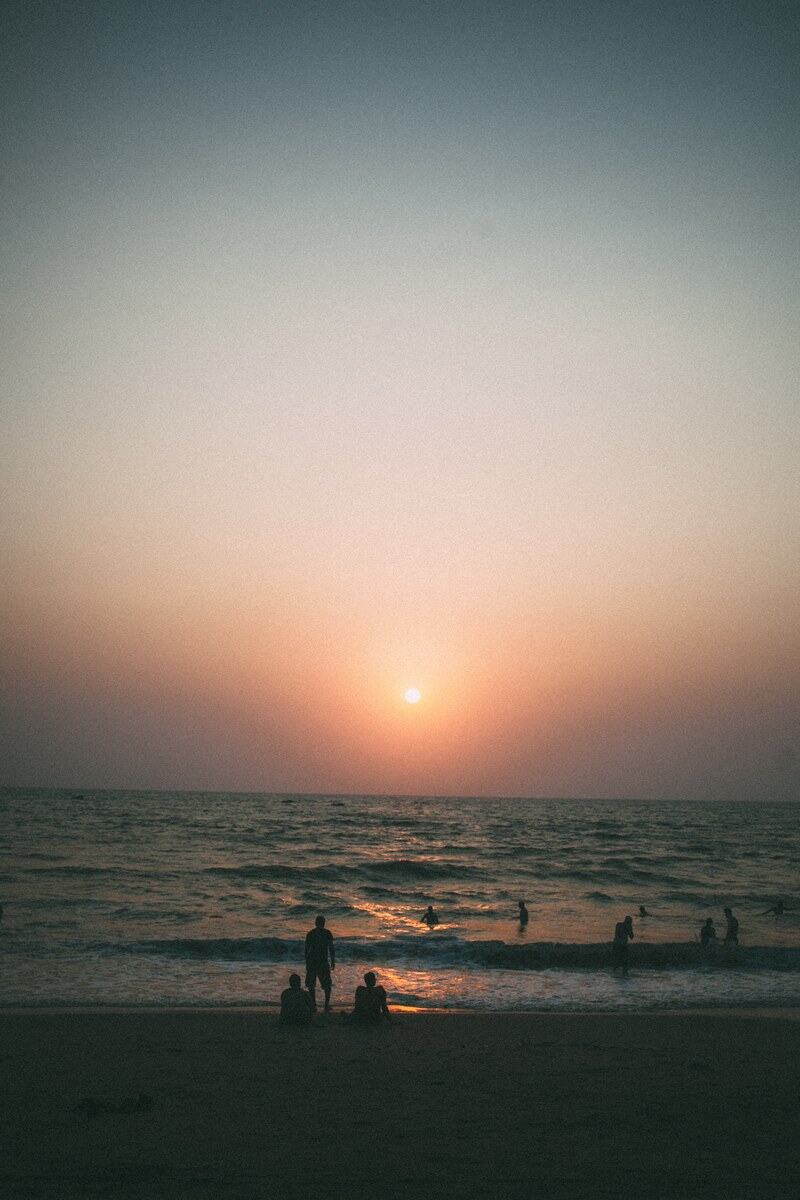 A quiet Goa beach sunset with people small against the water. print option