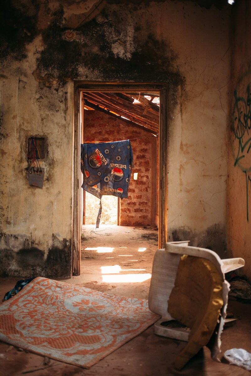 An abandoned Goa house interior opens to a bright doorway and weathered walls. print option