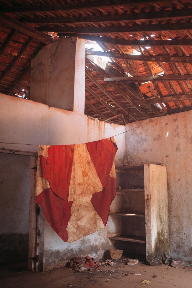 A weathered abandoned house interior in Goa, all worn walls, shadow and quiet travel texture. print option