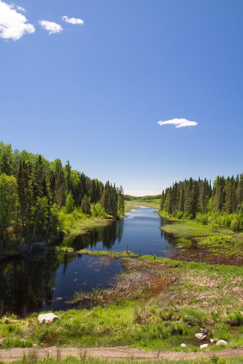 A narrow green water channel cuts through forested Northern Ontario near Sault Ste. Marie. print option