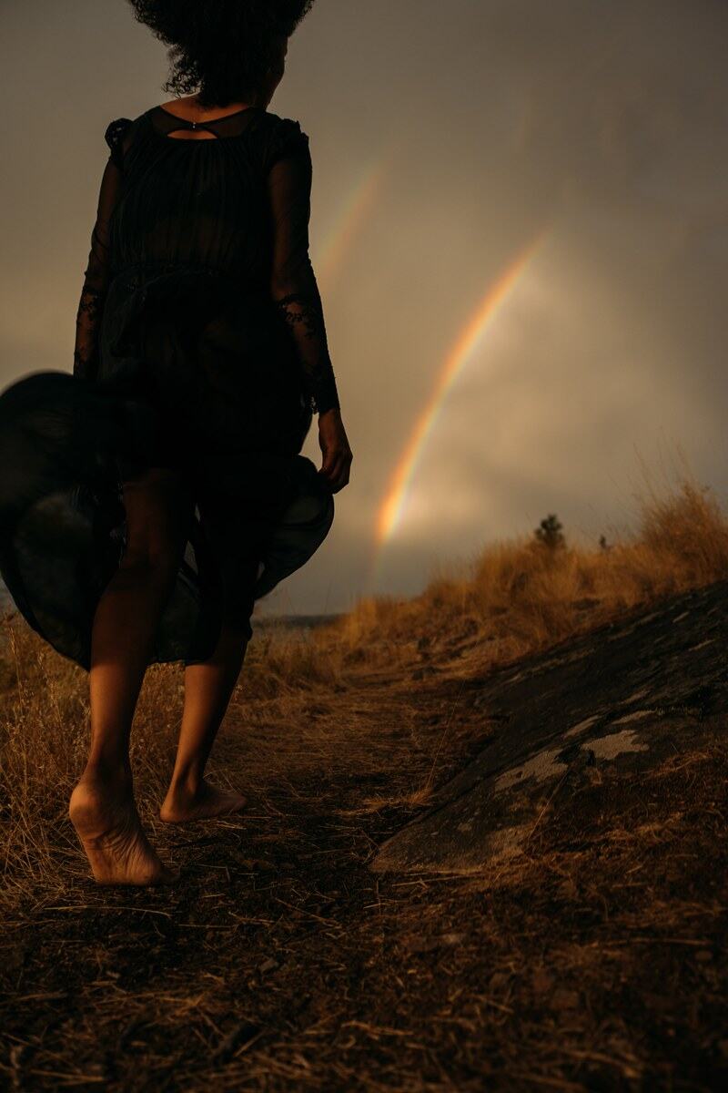 Rebekah walks barefoot through Okanagan Lake storm light with the rainbow rising behind her. print option