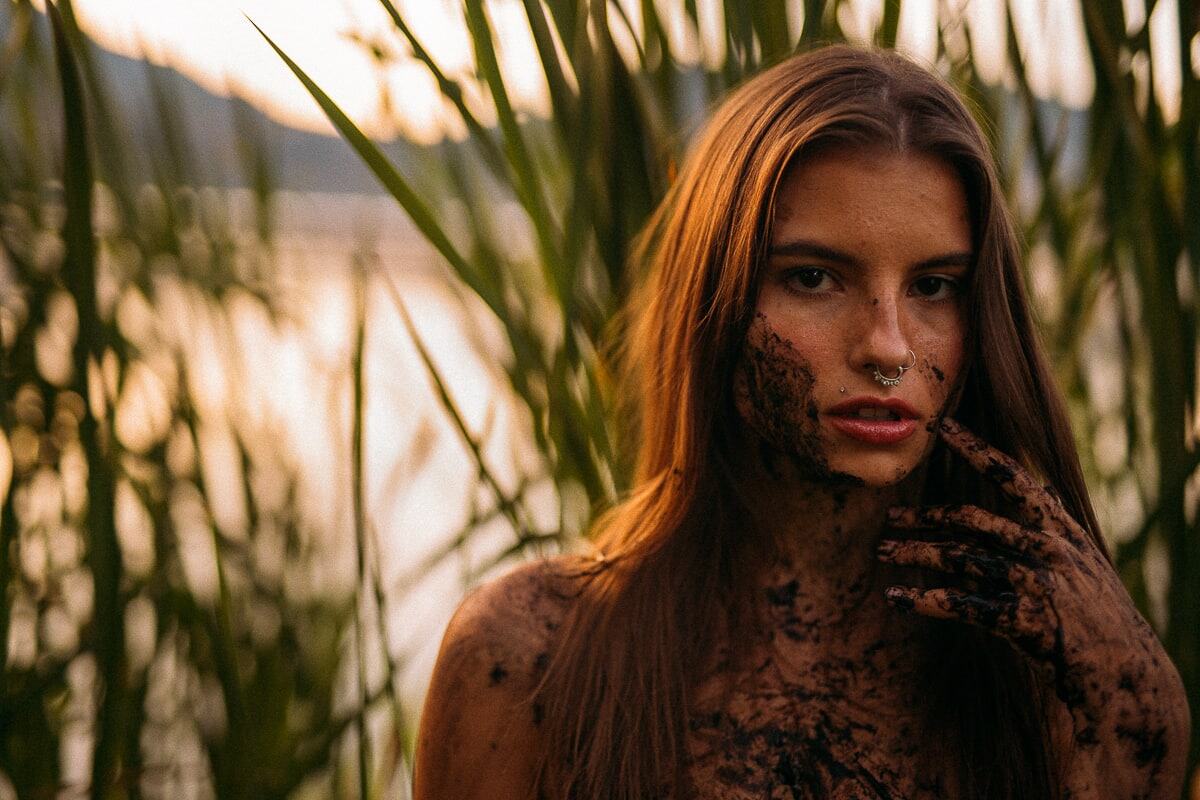 Mo in the Reeds story frame 1: A 2019 portrait archive story in reeds, body paint, low sun and green shadow.