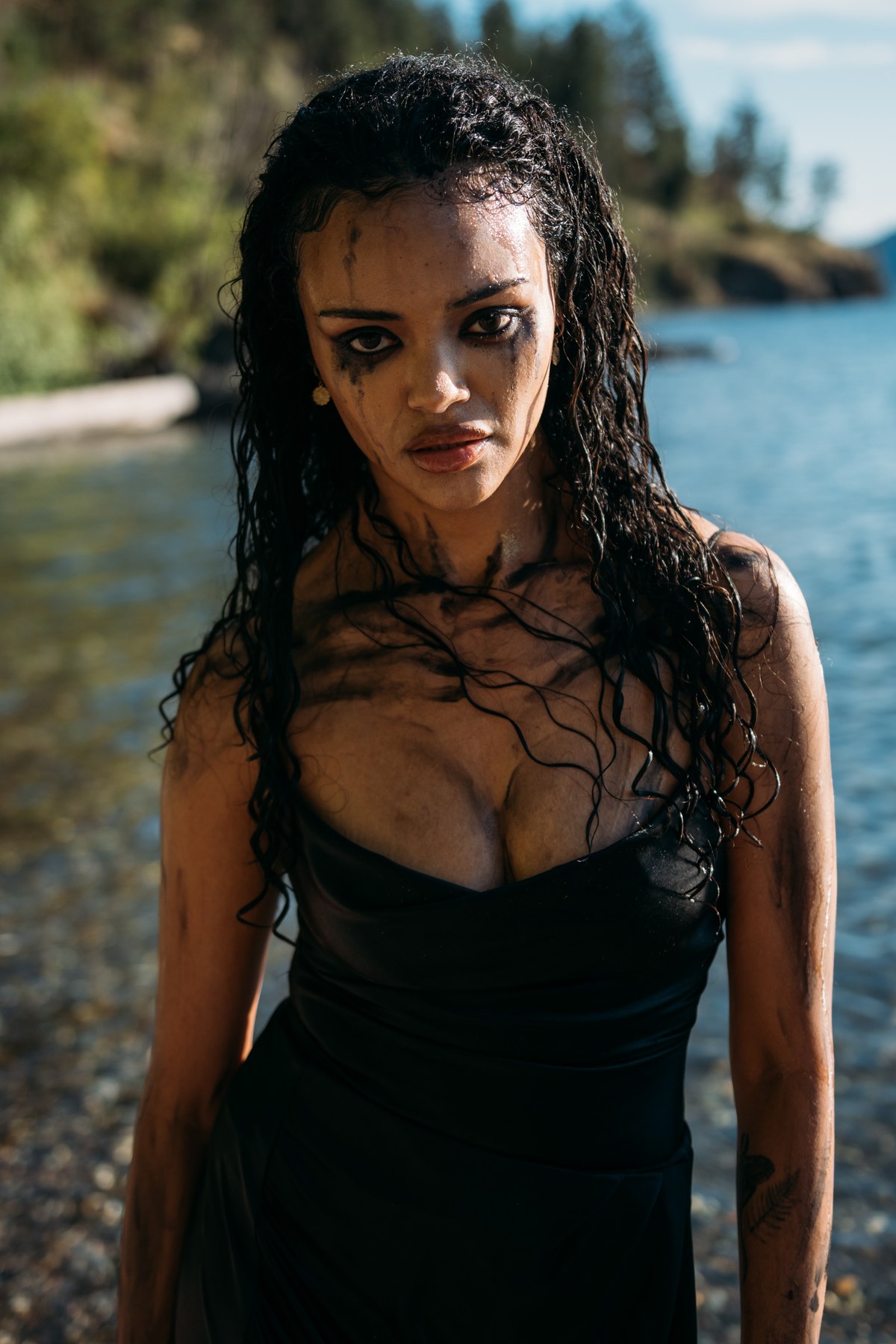 Alex by the Lake portraits story frame 1: Okanagan Lake portraits in Kelowna with black summer styling, rock, water, wind, direct expression and a cinematic beauty-portrait edge.
