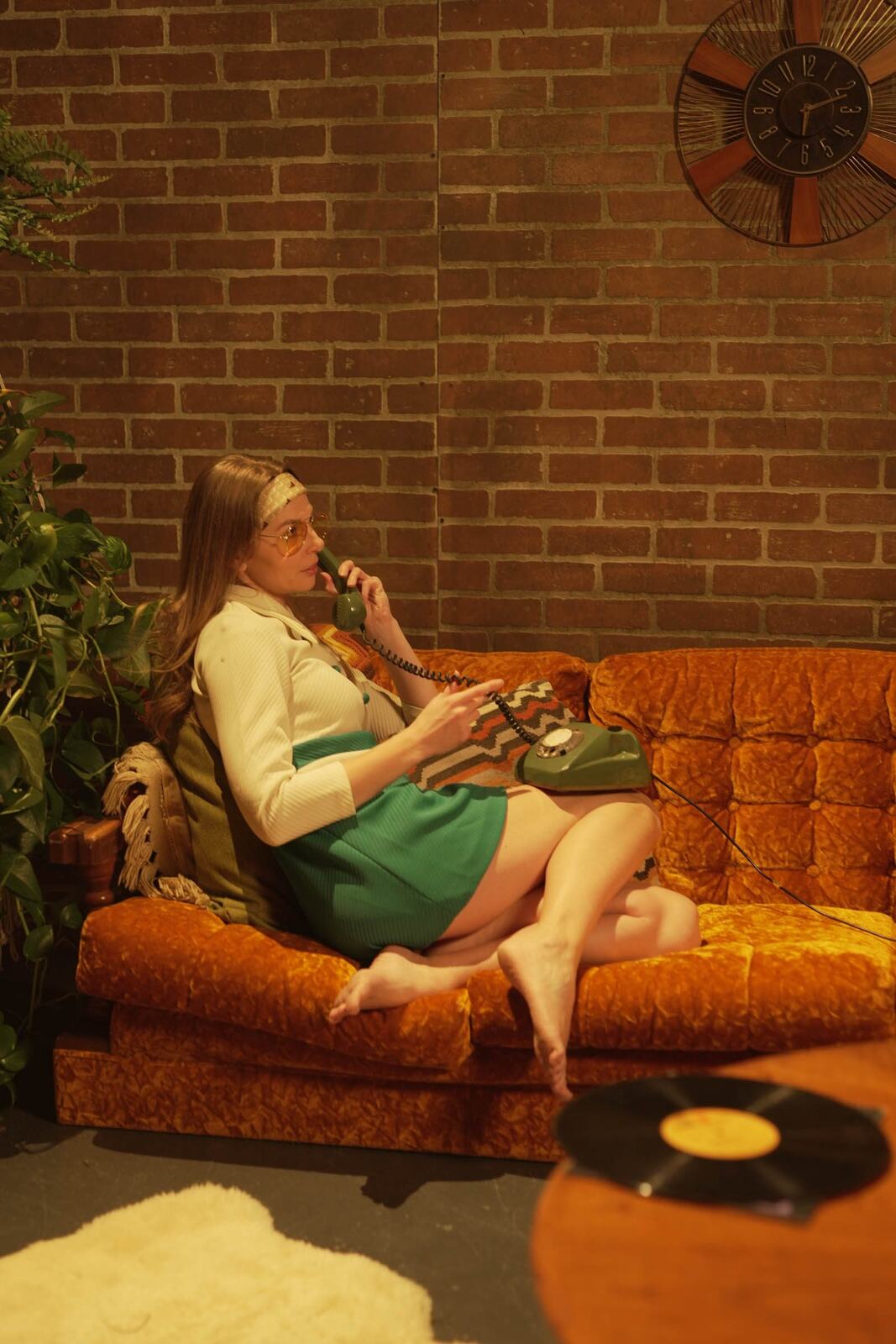 Angela in the 70s Lounge portraits story frame 10: A warm 70s lounge portrait story with yellow glasses, retro styling, couch texture and a softer studio mood.