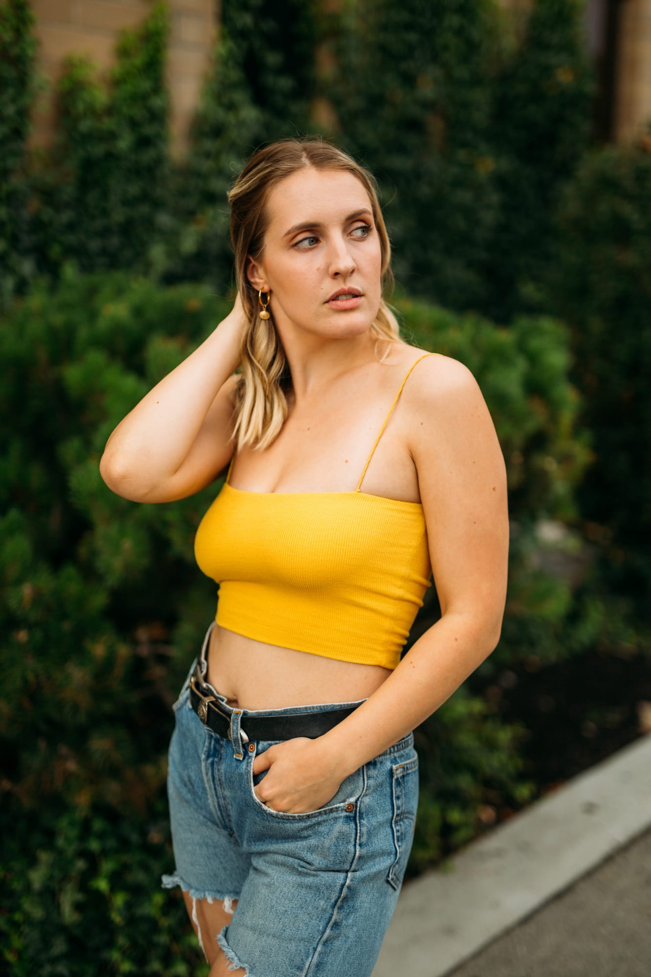 Brittany in Yellow and Blue portraits story frame 3: A two-look Kelowna portrait story for Brittany, led by the yellow styling and dark green texture, then moving into blue lakeside frames and a soft rainbow-bokeh finish.