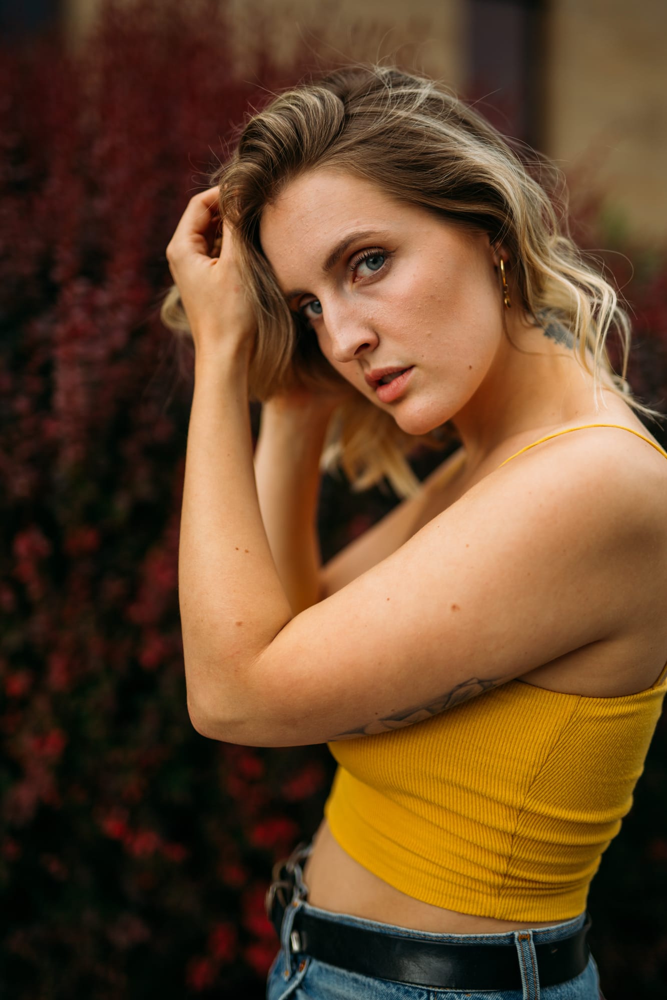 Brittany in Yellow and Blue portraits story frame 5: A two-look Kelowna portrait story for Brittany, led by the yellow styling and dark green texture, then moving into blue lakeside frames and a soft rainbow-bokeh finish.