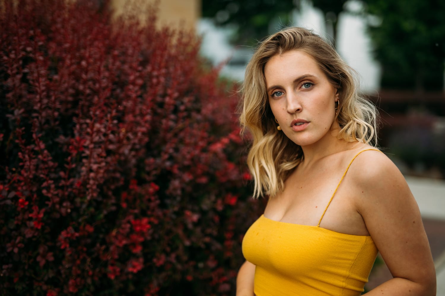 Brittany in Yellow and Blue portraits story frame 7: A two-look Kelowna portrait story for Brittany, led by the yellow styling and dark green texture, then moving into blue lakeside frames and a soft rainbow-bokeh finish.