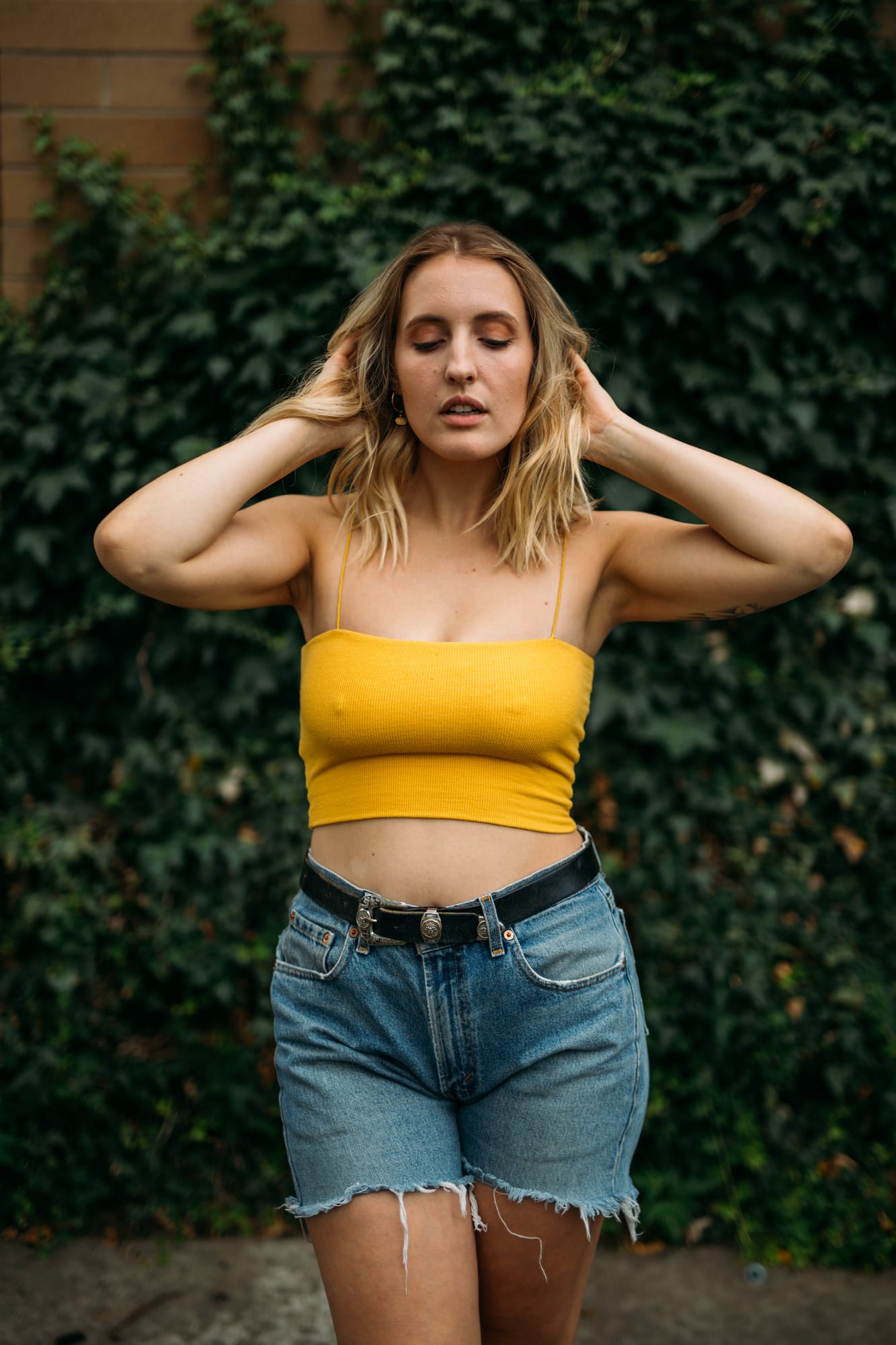 Brittany in Yellow and Blue portraits story frame 9: A two-look Kelowna portrait story for Brittany, led by the yellow styling and dark green texture, then moving into blue lakeside frames and a soft rainbow-bokeh finish.