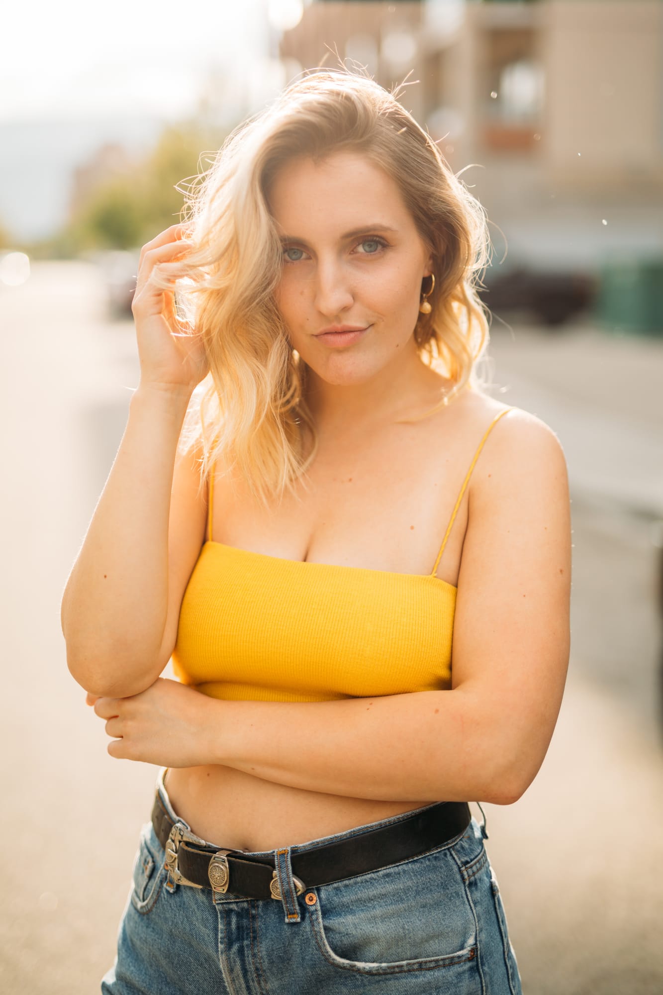 Brittany in Yellow and Blue portraits story frame 10: A two-look Kelowna portrait story for Brittany, led by the yellow styling and dark green texture, then moving into blue lakeside frames and a soft rainbow-bokeh finish.