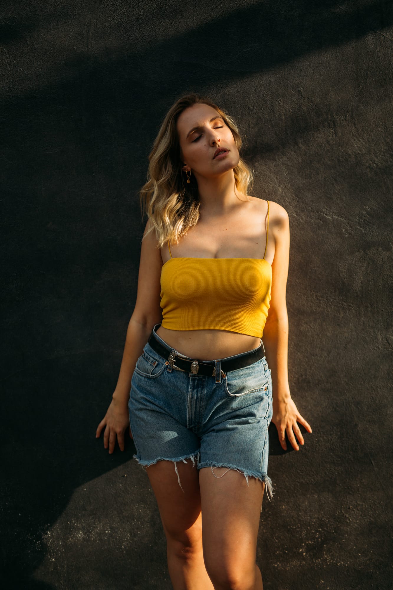 Brittany in Yellow and Blue portraits story frame 13: A two-look Kelowna portrait story for Brittany, led by the yellow styling and dark green texture, then moving into blue lakeside frames and a soft rainbow-bokeh finish.