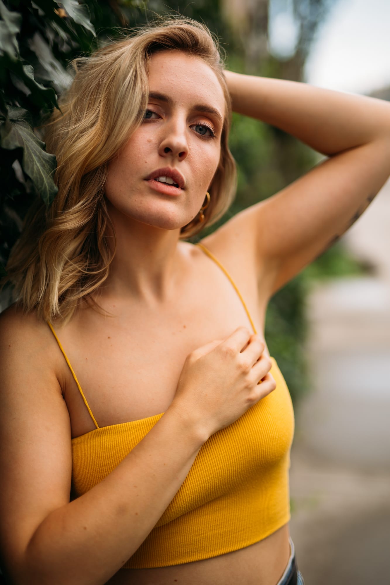 Brittany in Yellow and Blue portraits story frame 18: A two-look Kelowna portrait story for Brittany, led by the yellow styling and dark green texture, then moving into blue lakeside frames and a soft rainbow-bokeh finish.