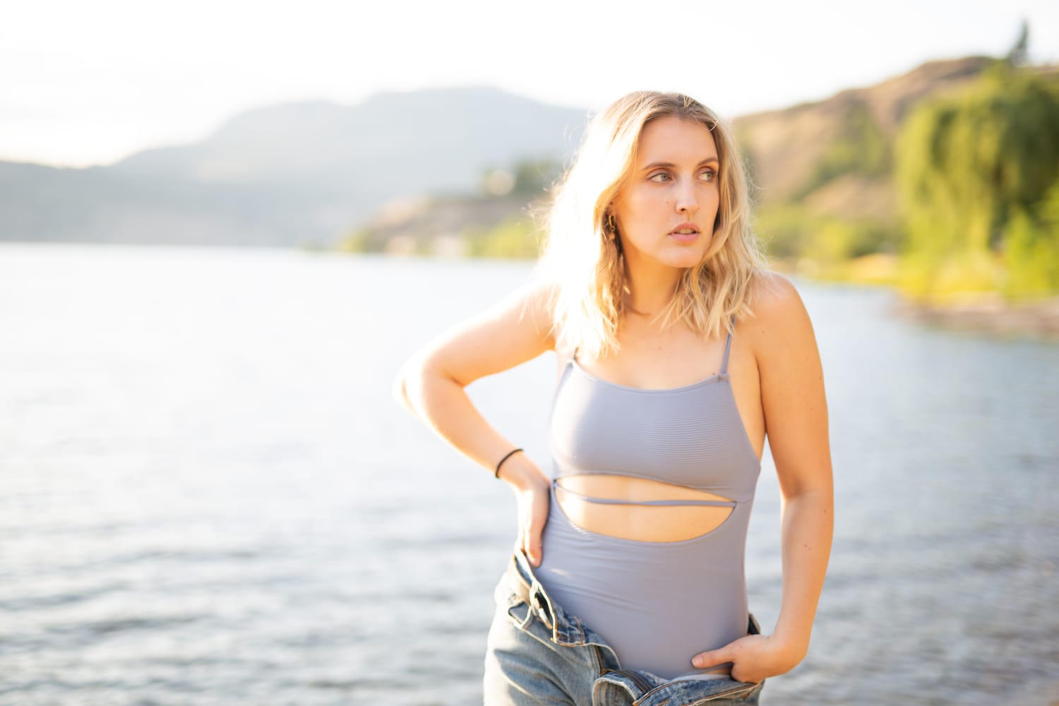 Brittany in Yellow and Blue portraits story frame 20: A two-look Kelowna portrait story for Brittany, led by the yellow styling and dark green texture, then moving into blue lakeside frames and a soft rainbow-bokeh finish.