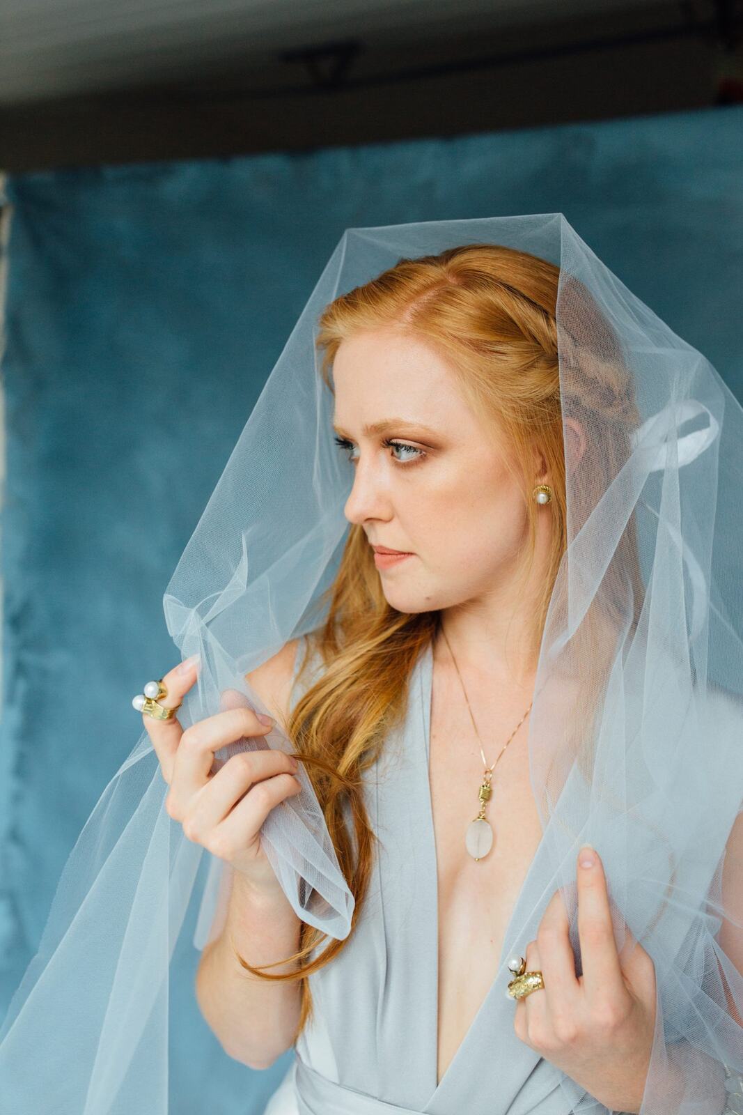 Catherine portraits story frame 2: Fashion portraits with Catherine from a White Willow Photography-designed collaboration near Salmon Arm, with pale blue styling, jewellery, veil and a painted studio backdrop.
