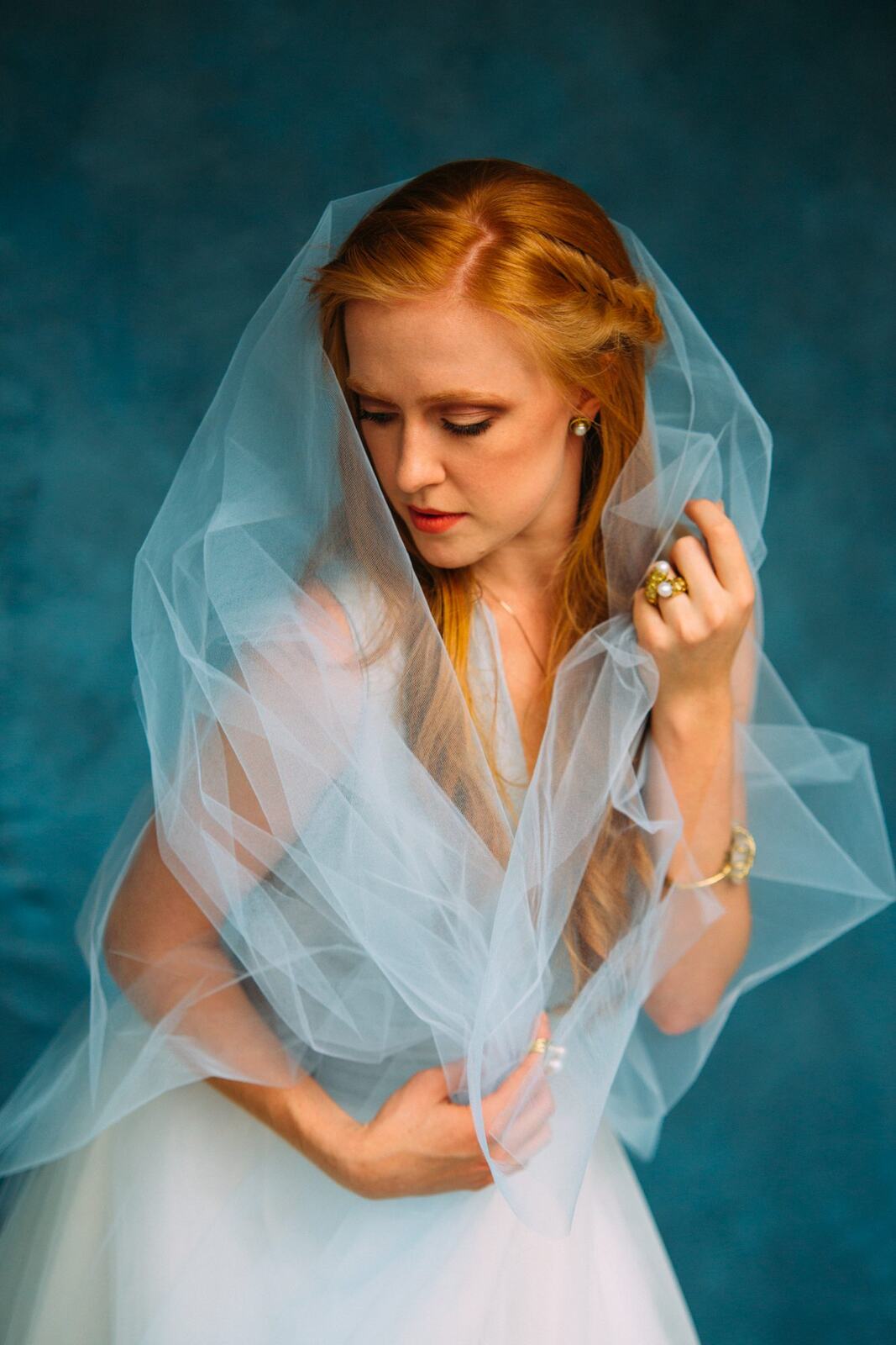 Catherine portraits story frame 6: Fashion portraits with Catherine from a White Willow Photography-designed collaboration near Salmon Arm, with pale blue styling, jewellery, veil and a painted studio backdrop.