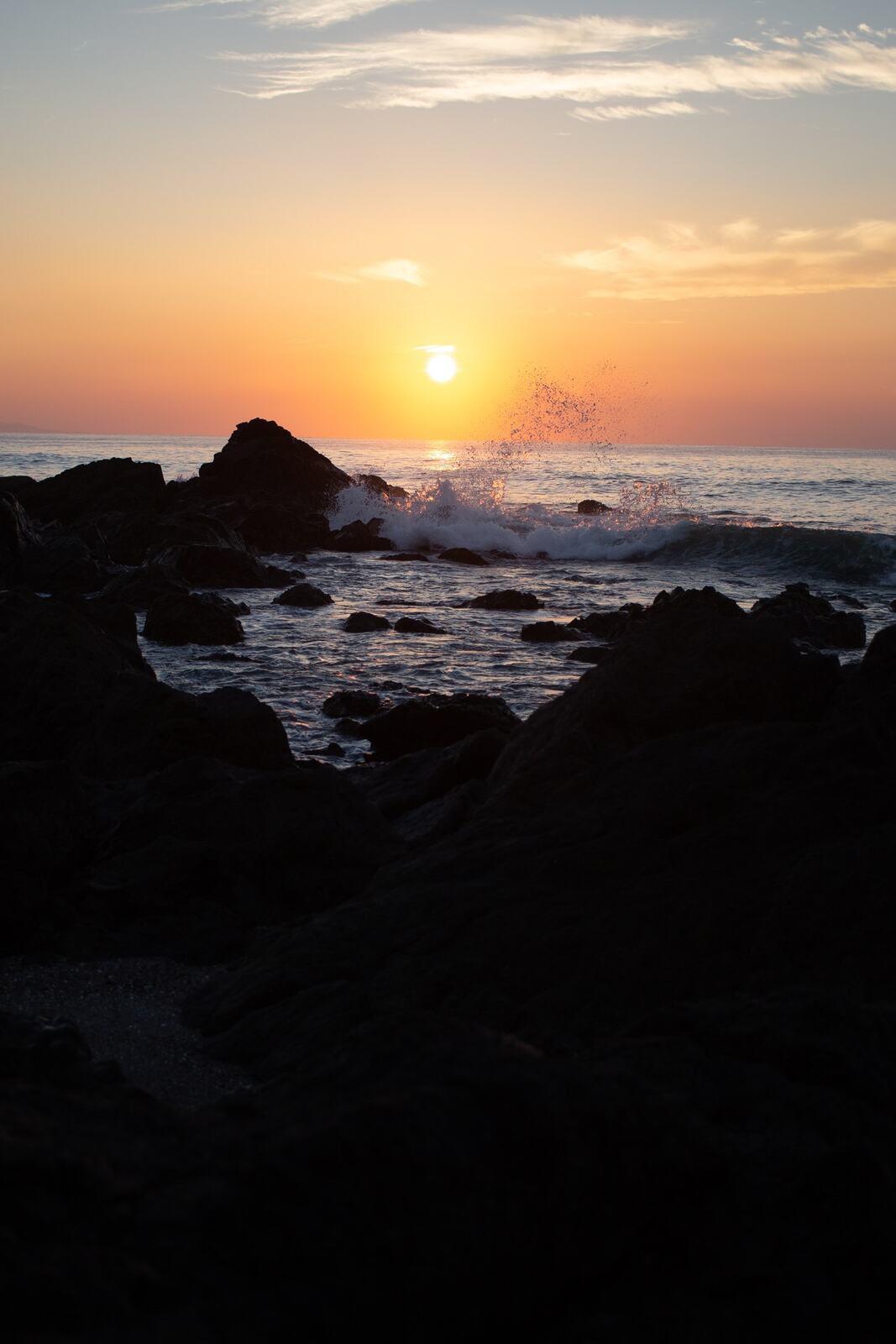 Sunset over dark Costa Rica shoreline rocks