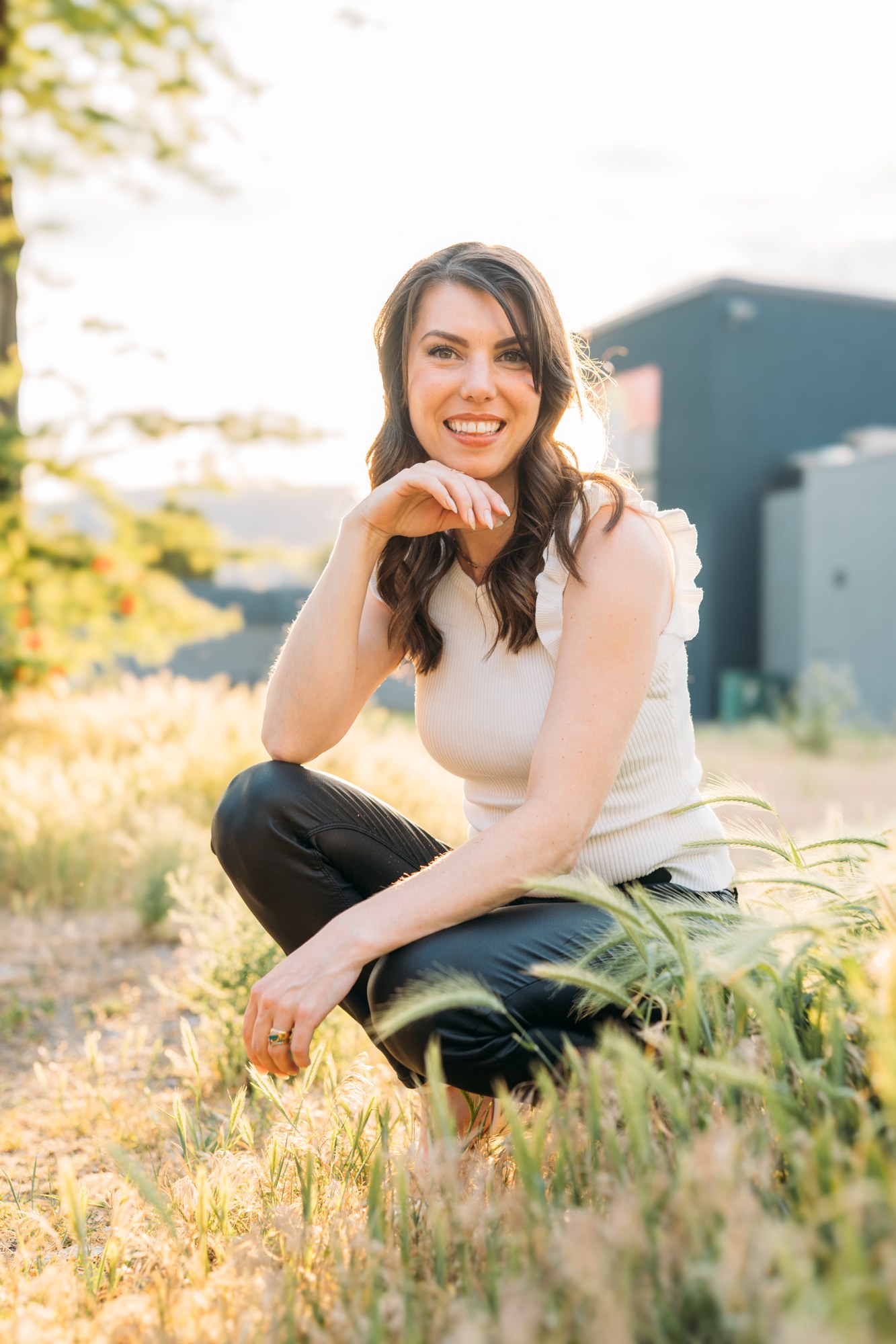 Diva Den Team Portraits: Lindsay seated in the sunlit grass.