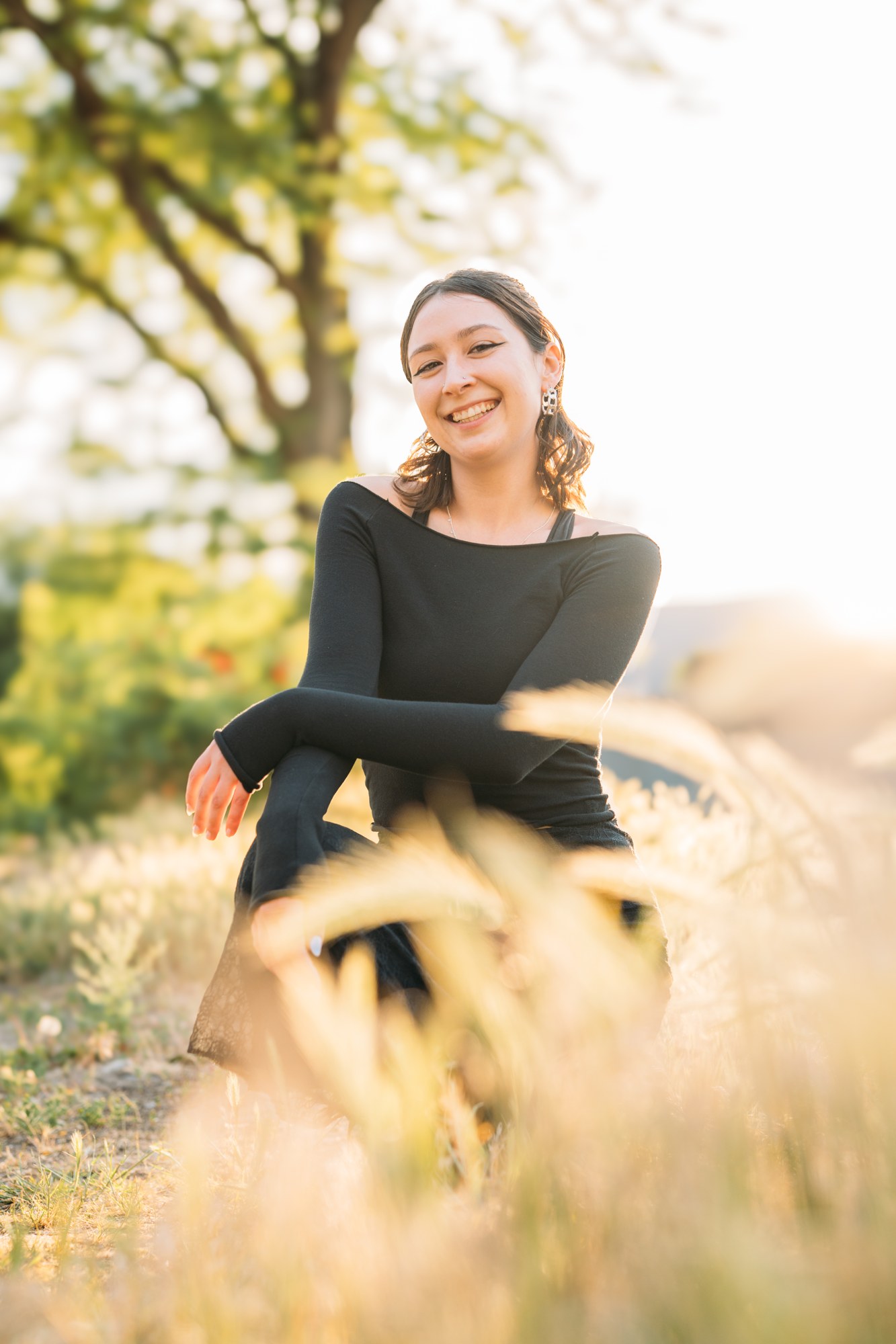 Diva Den Team Portraits: Abby laughing while seated in the grass.