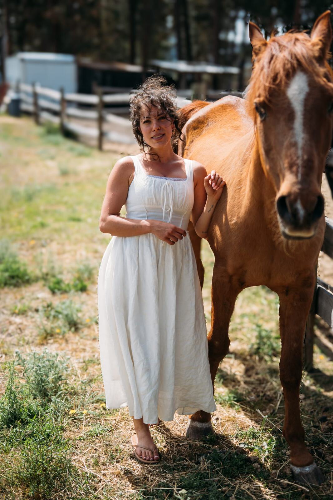Giuliana at LoveReins portraits story frame 4: Equestrian portrait session at Love Reins Ranch in Lake Country, BC, with Giuliana, horses, white-dress portraits, Western cowgirl styling, ranch fencing, riding frames and warm Okanagan light..