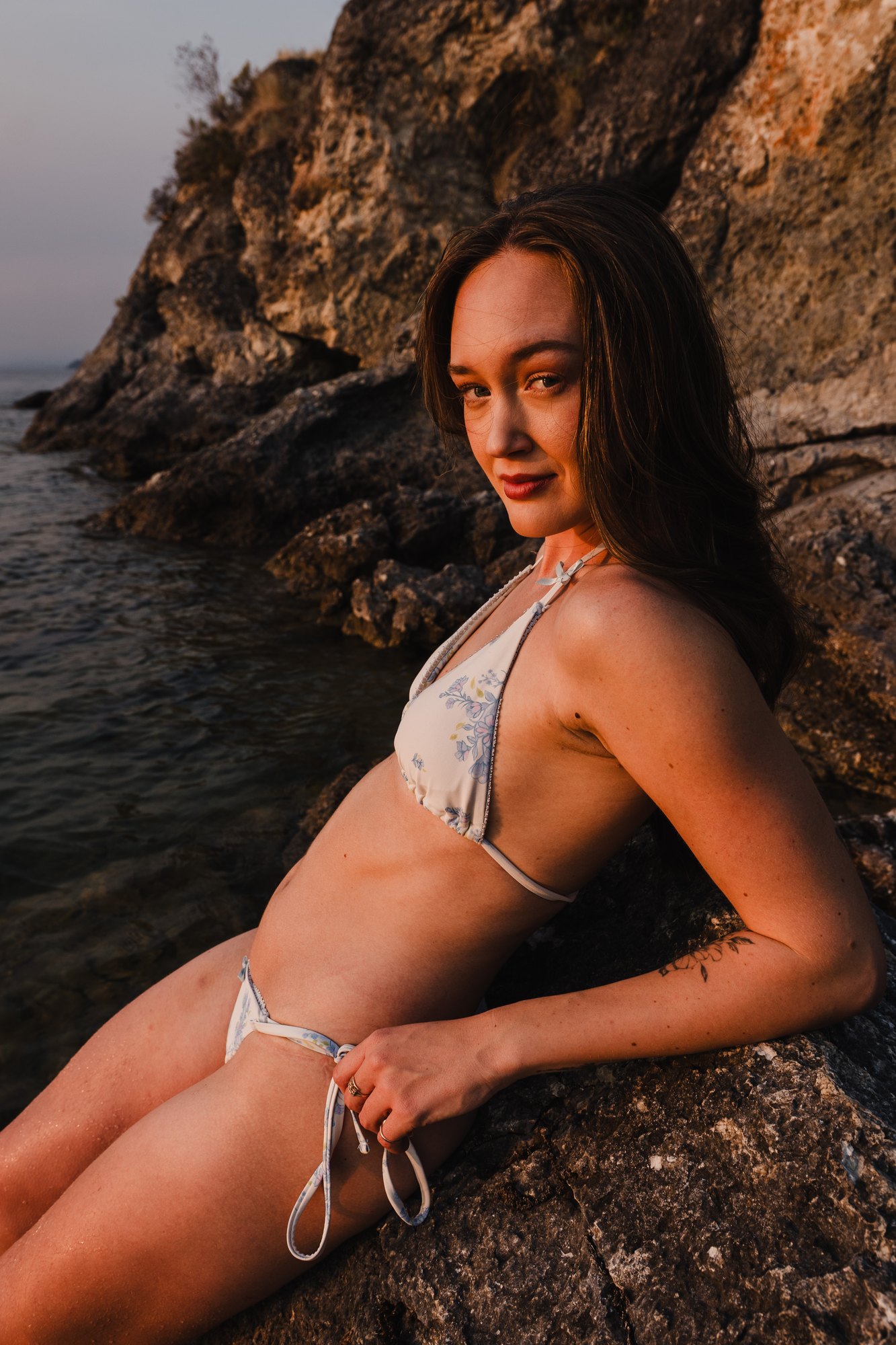 Holly — seated portrait on the sunlit shoreline rocks