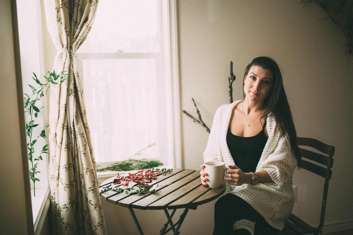 Jasmin by the Window portrait story frame 7: Window-light portraits with Jasmin beside a small table, tea and winter greenery in Kelowna, British Columbia.