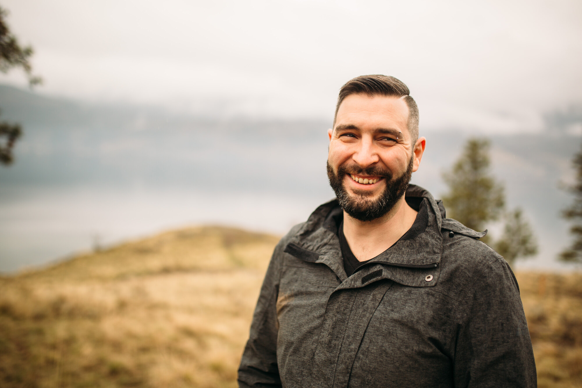 Jeremy laughing in a warm close portrait above the lake.
