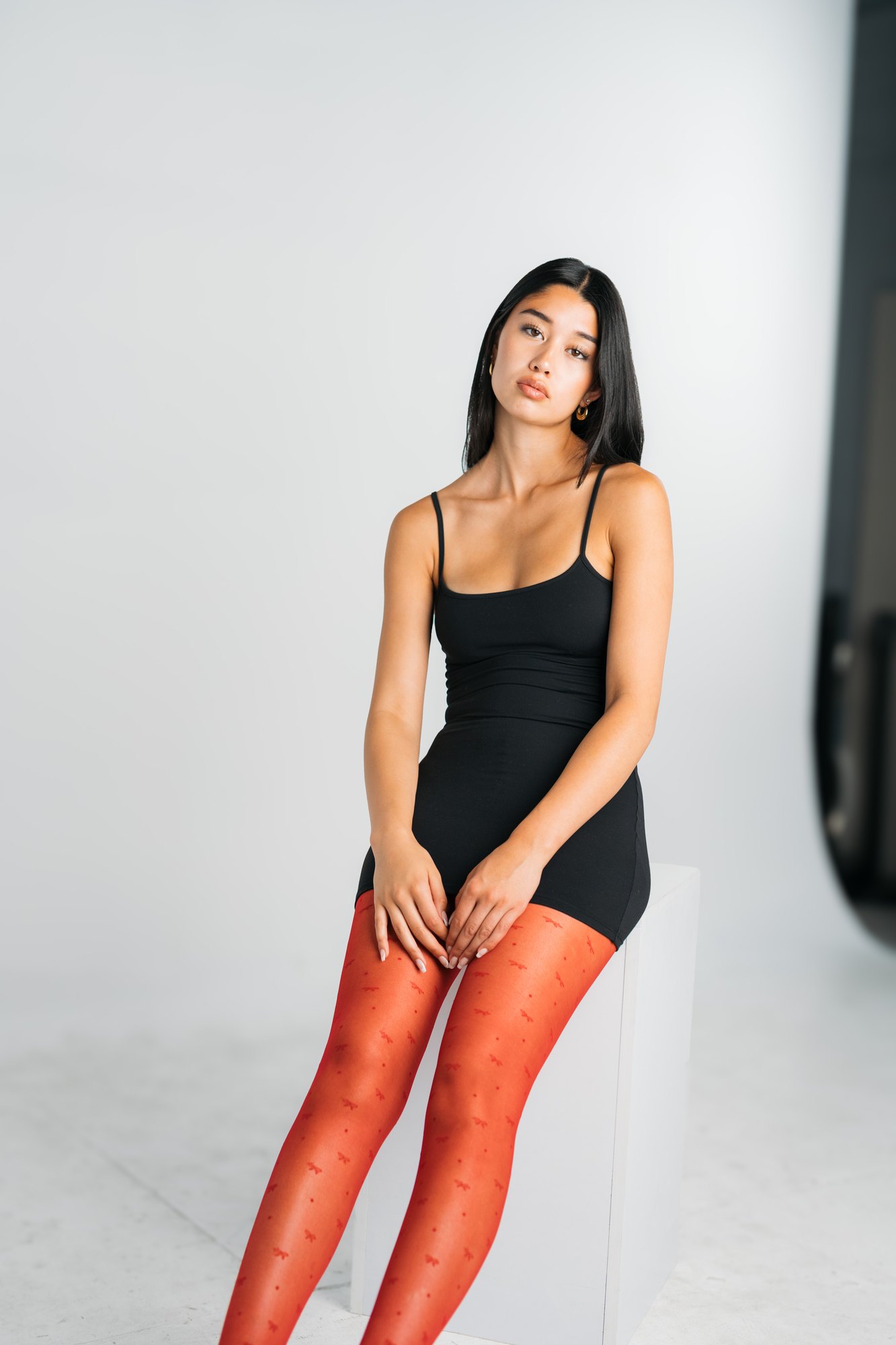 Julia Crofoot — sitting on a white block with red tights in view