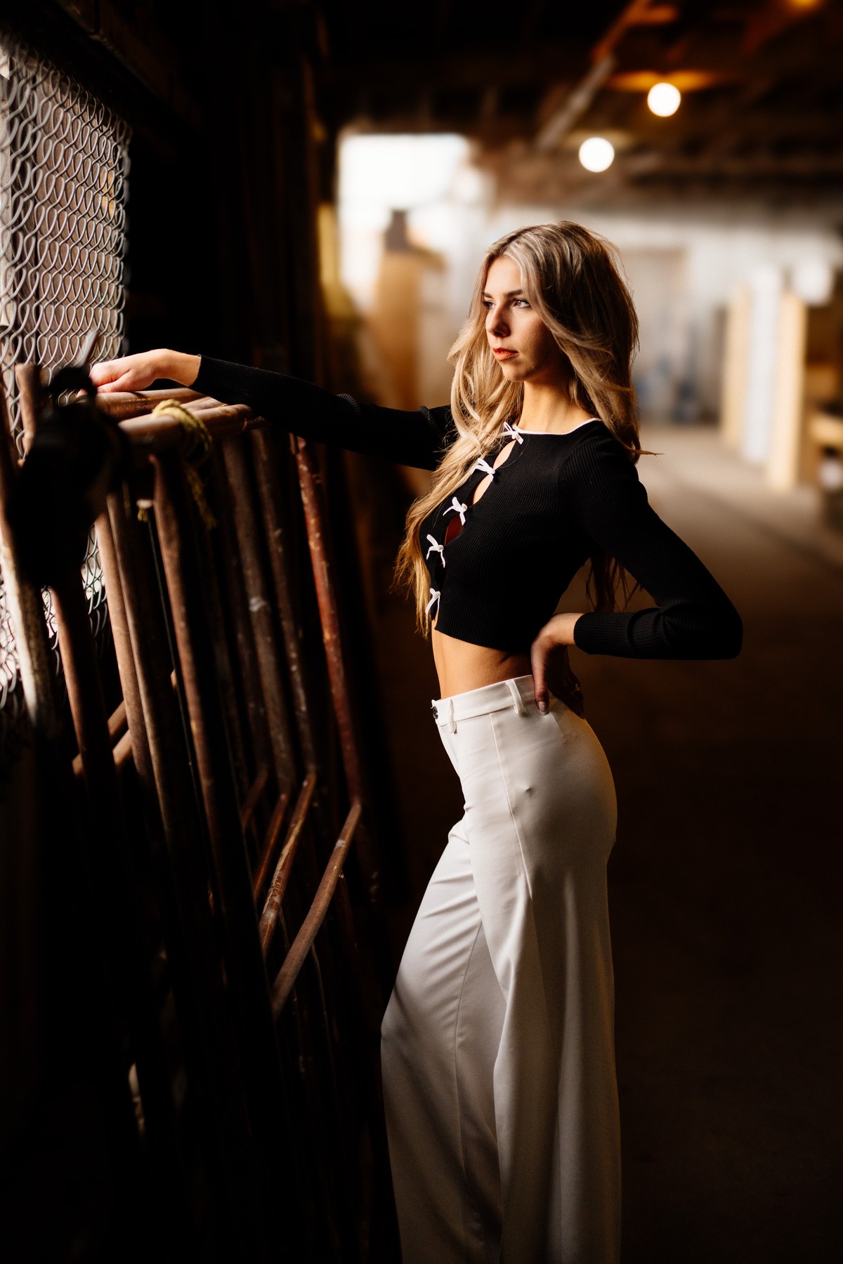Kaylee in Clouds portraits story frame 9: Kelowna studio portraits with cloud styling, warm industrial light, black lace-up wardrobe, white pants and soft editorial glamour.
