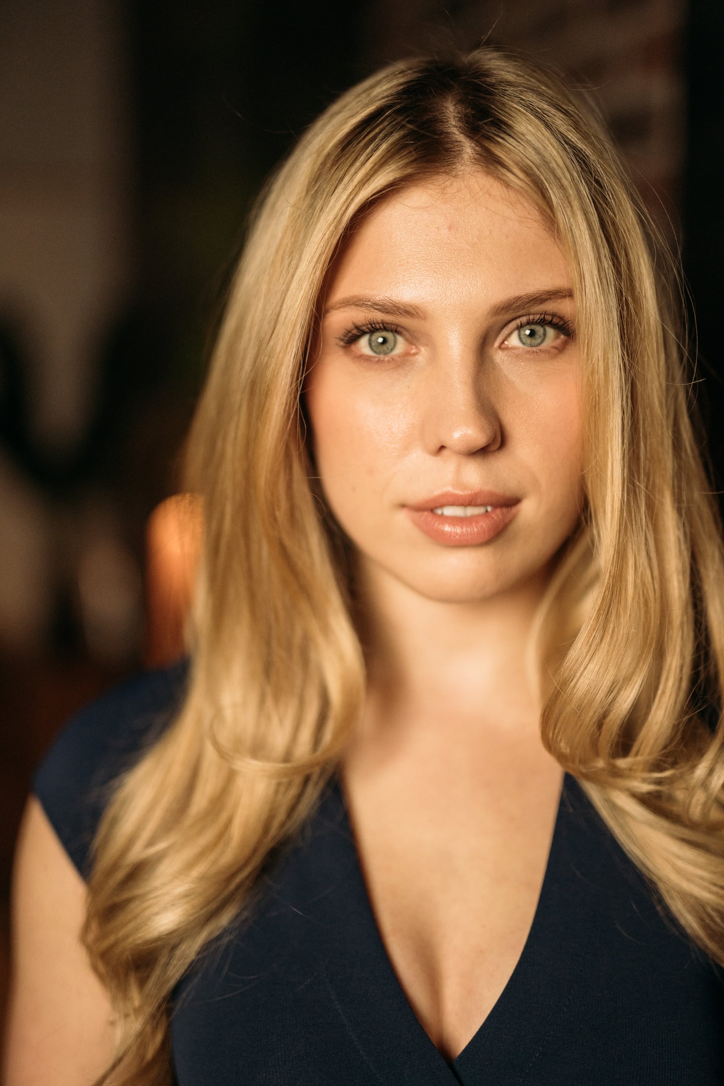 Kennedy looking directly into the camera in a navy dress