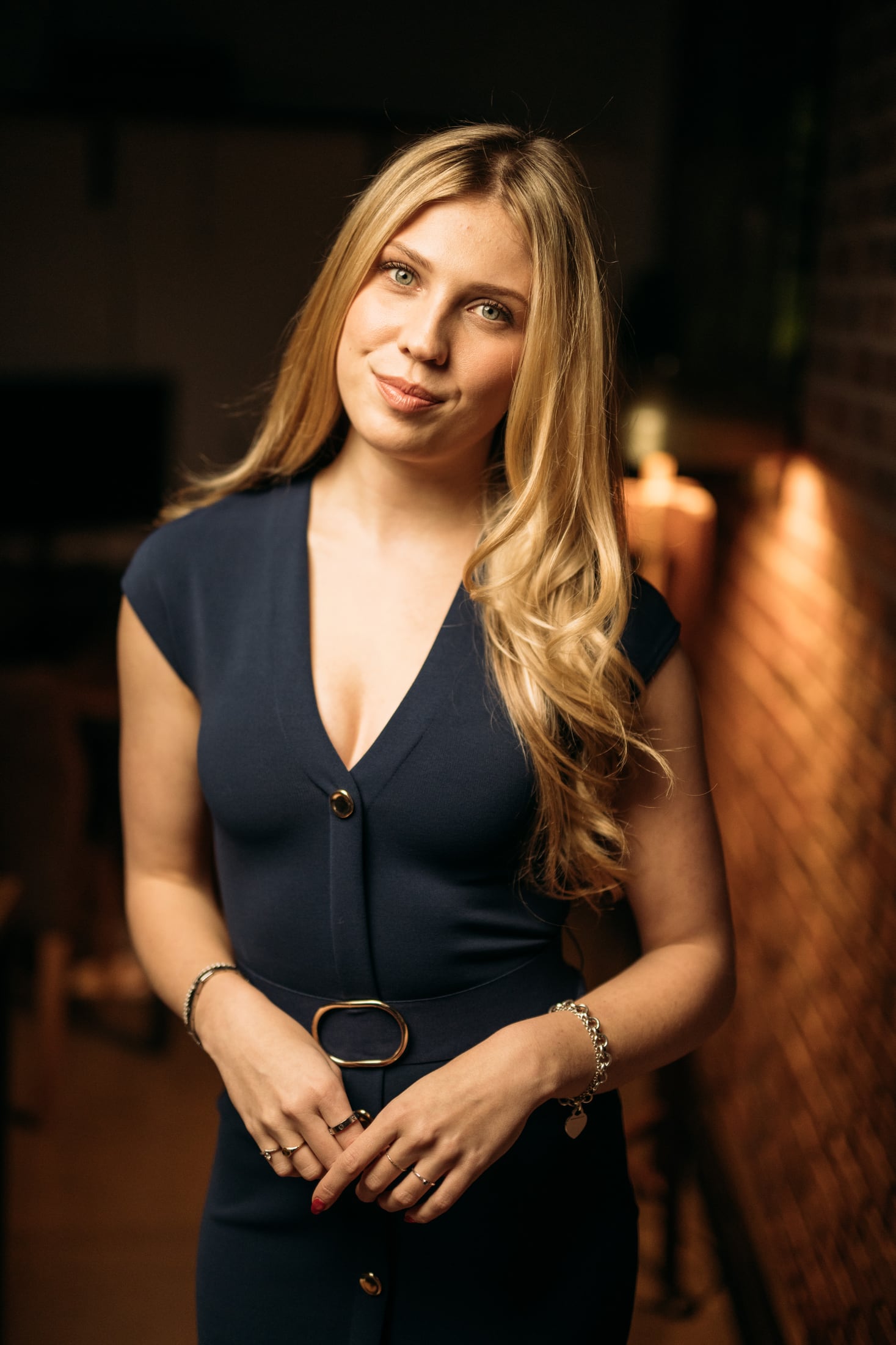 Kennedy in a navy dress with her head tilted