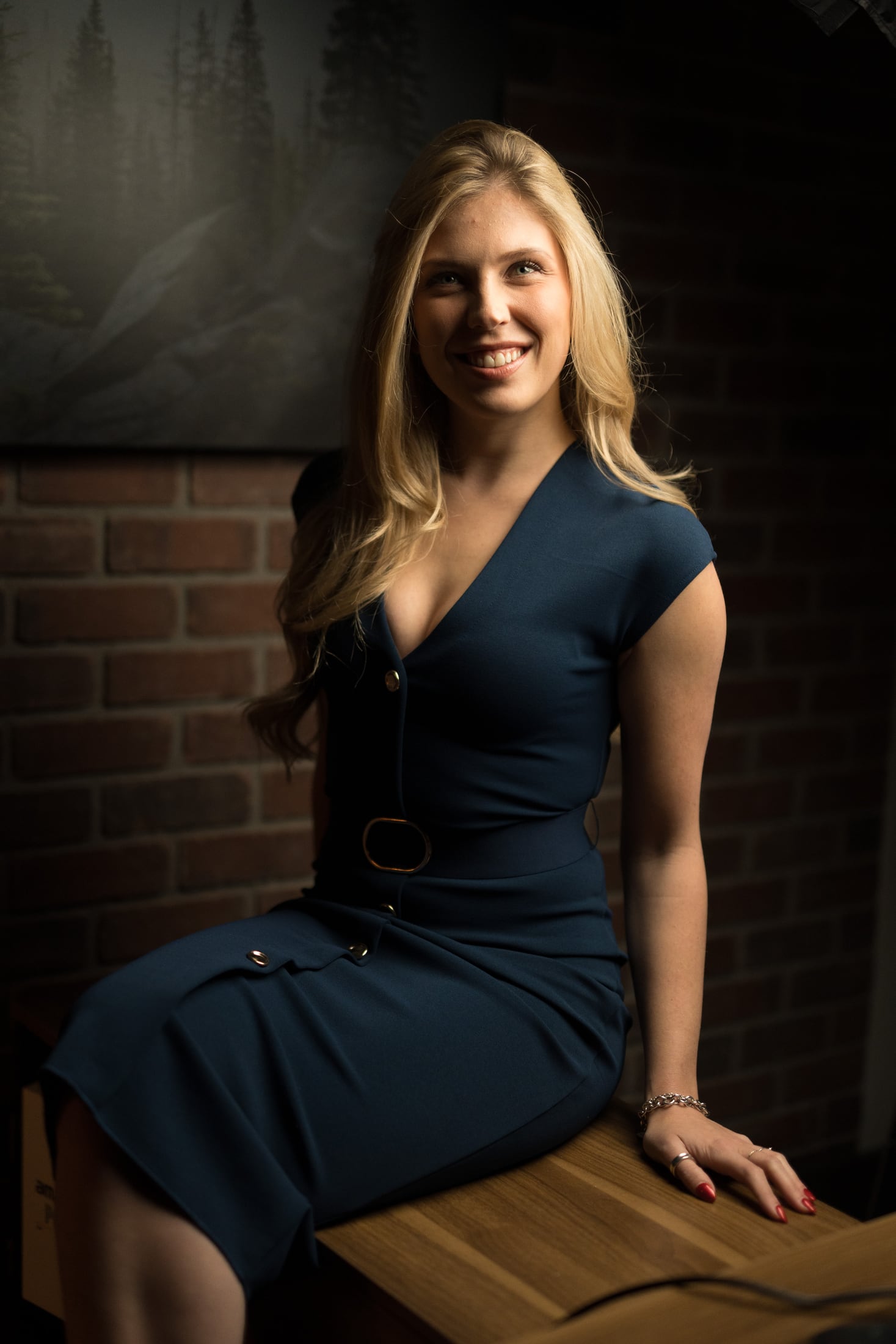 Kennedy smiling while seated beside a brick wall