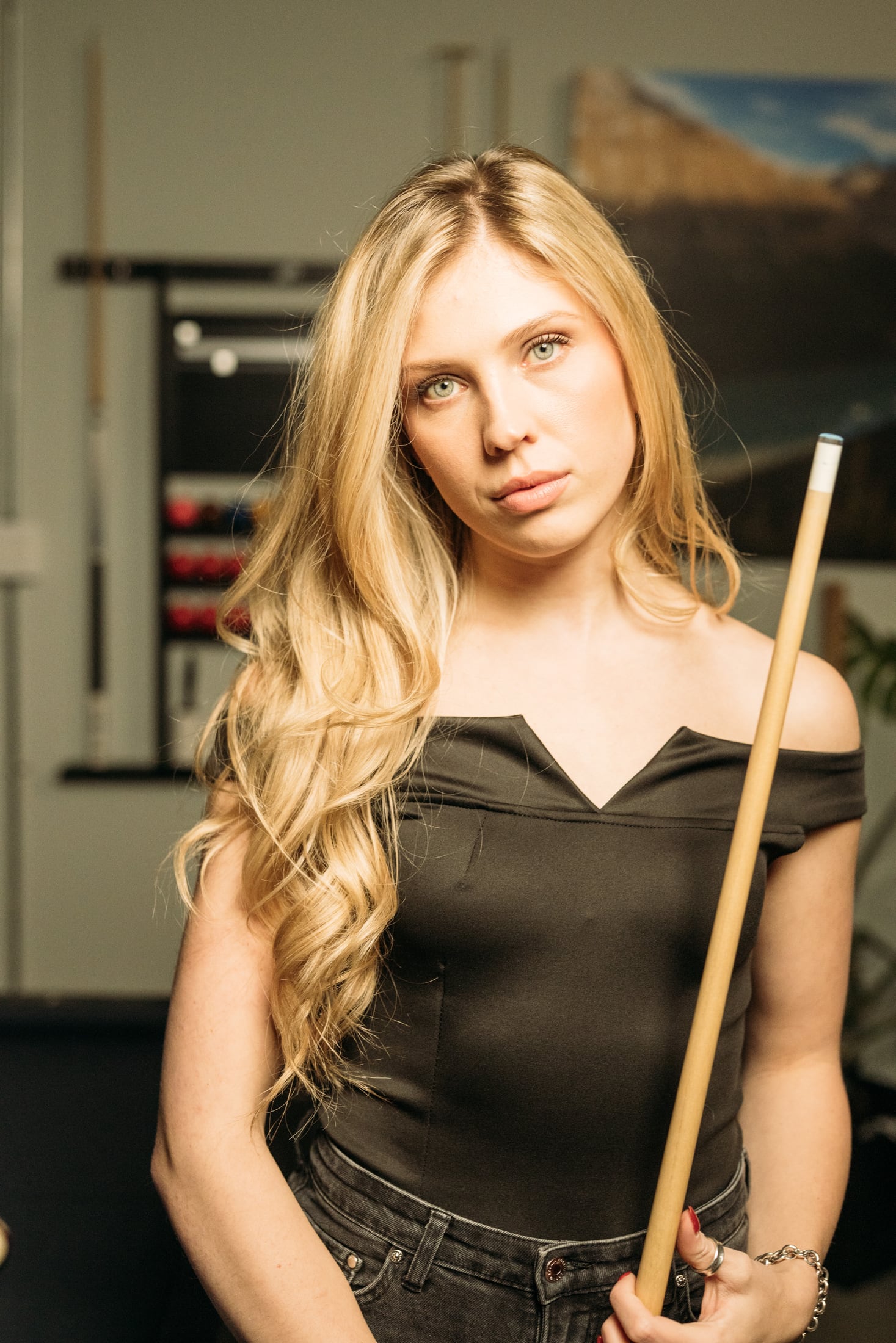 Kennedy holding a pool cue beside the pool hall