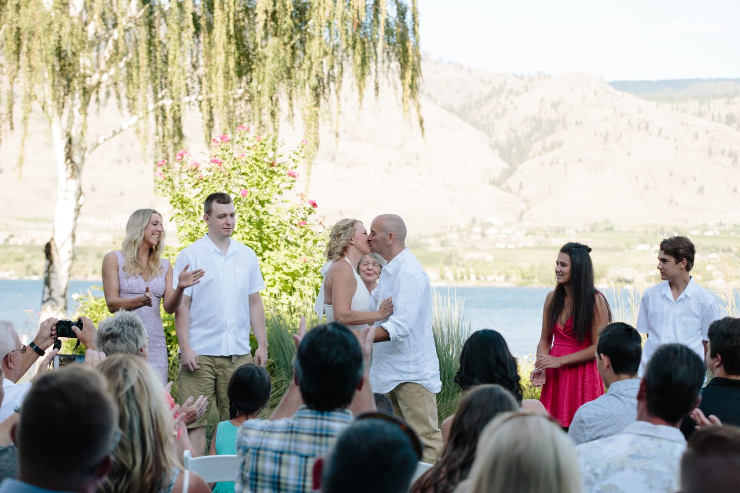 Leeanne and Kelly weddings story frame 23: A Watermark Beach Resort wedding in Osoyoos, built around lakefront context, grown-family connection and careful, big-hearted coverage..