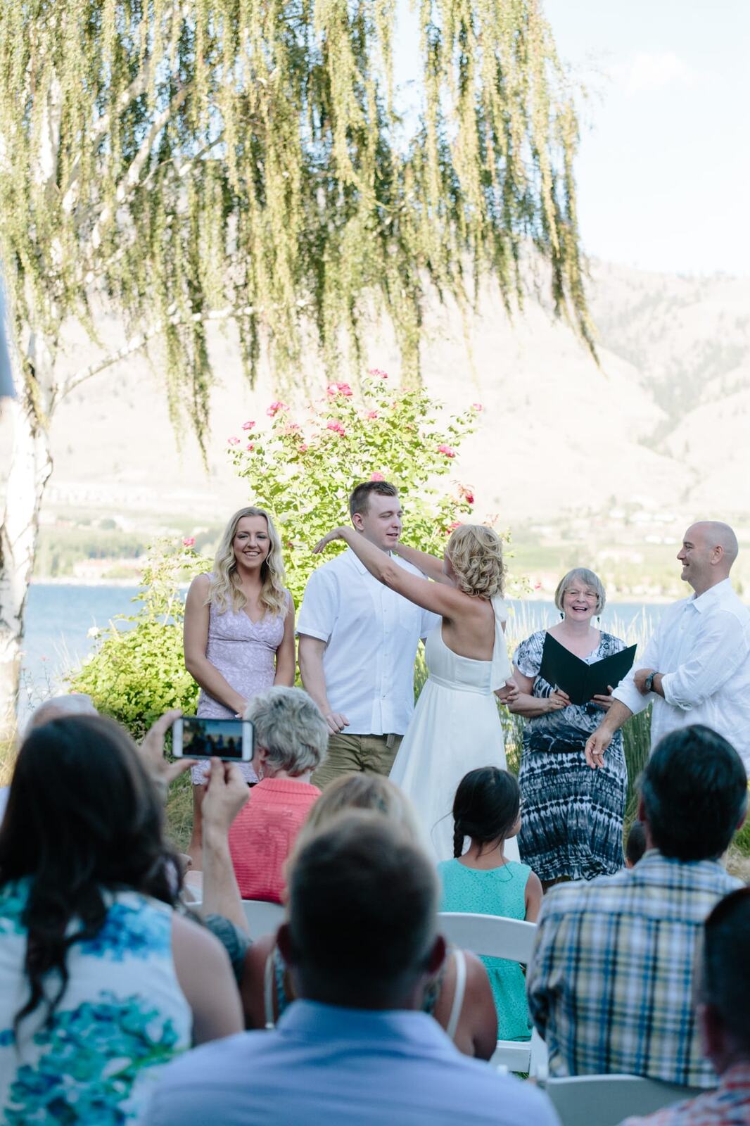 Leeanne and Kelly weddings story frame 20: A Watermark Beach Resort wedding in Osoyoos, built around lakefront context, grown-family connection and careful, big-hearted coverage..