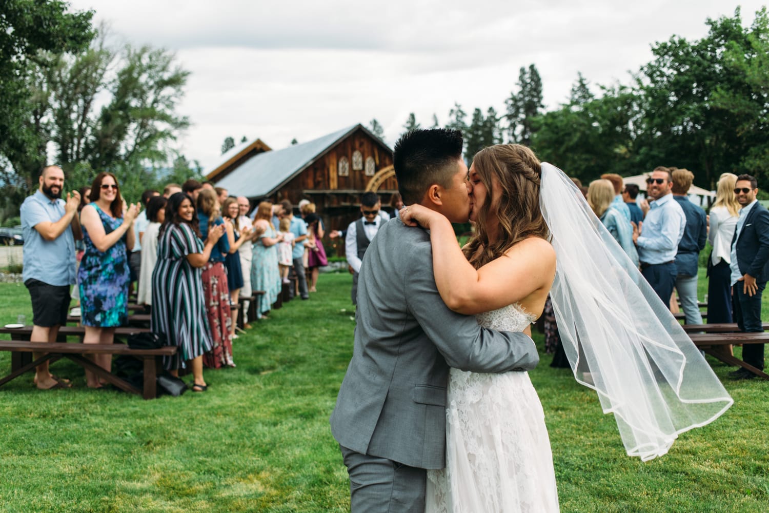 Leslie and Gerome weddings story frame 19: A Brook & Barn - Casorso Heritage Farm wedding in Kelowna, with orchard details, outbuildings, lawn games and a familiar friend-party feeling..