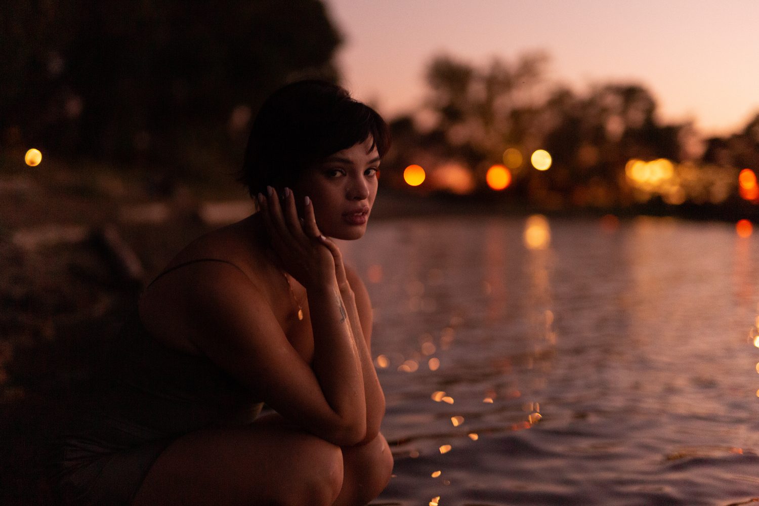 Lucy at the Water’s Edge portraits story frame 16: Lucy at the water’s edge as sunset slips into moonlight, moving from the shoreline and rocks to quiet close portraits and a warm-lit garden after dark. Photographed in Kelowna, BC.