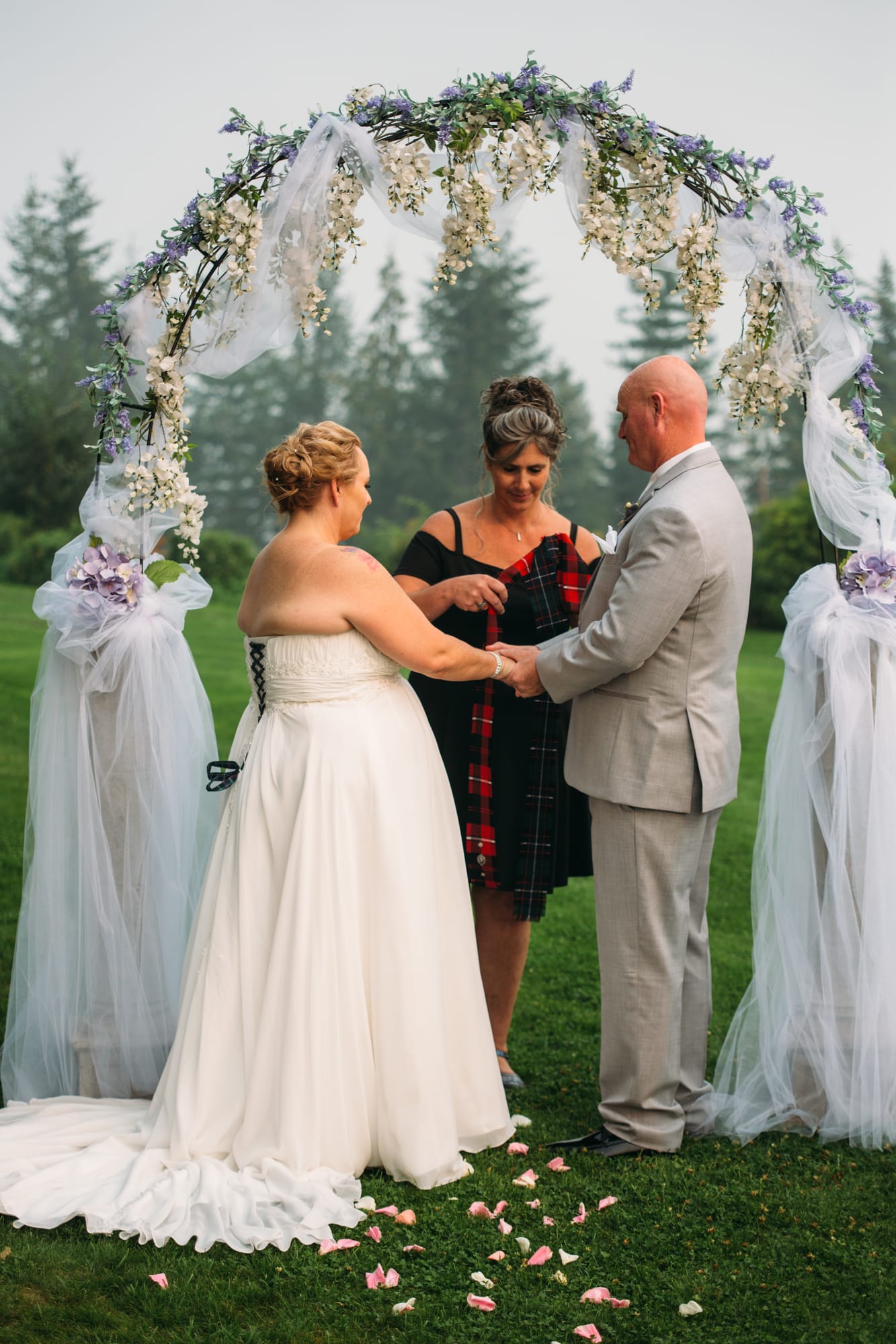Marie and Mark weddings story frame 20: A Mabel Lake Airpark wedding in the North Okanagan, with grass-runway scenery, open-air photos and sweet family help around makeup, flowers and petals..