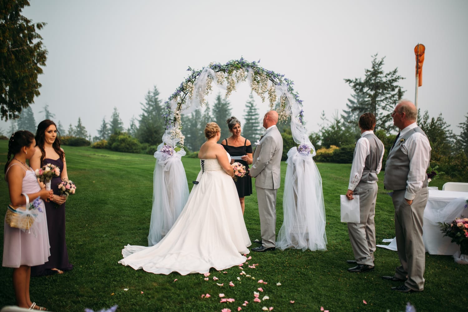 Marie and Mark weddings story frame 24: A Mabel Lake Airpark wedding in the North Okanagan, with grass-runway scenery, open-air photos and sweet family help around makeup, flowers and petals..