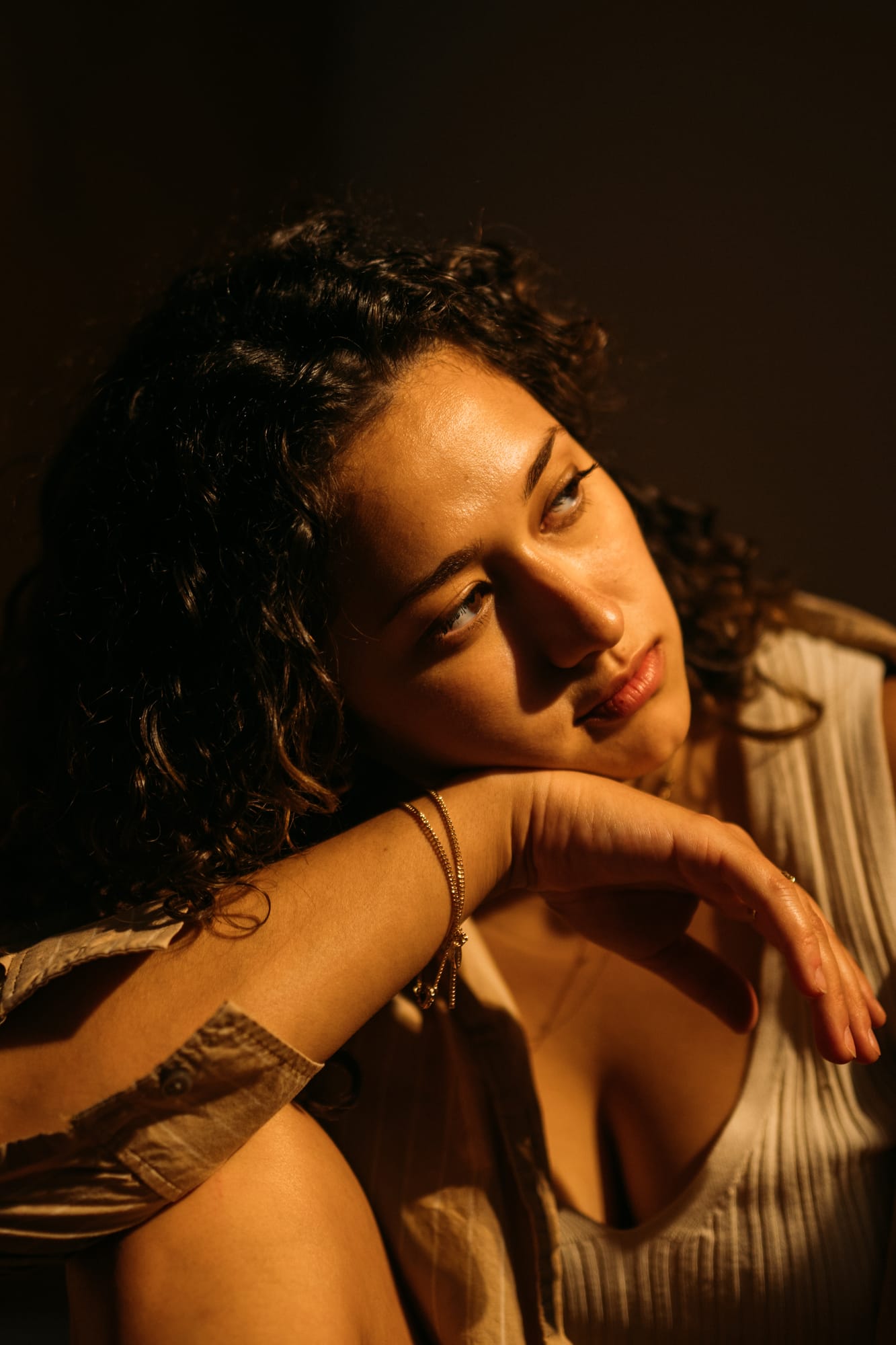 Marina in Warm Window Light portraits story frame 1: Marina in warm indoor light, with amber shadow, denim, black robe, green styling and an intimate editorial portrait mood.