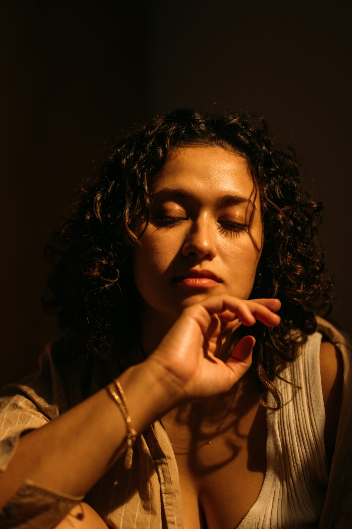 Marina in Warm Window Light portraits story frame 2: Marina in warm indoor light, with amber shadow, denim, black robe, green styling and an intimate editorial portrait mood.