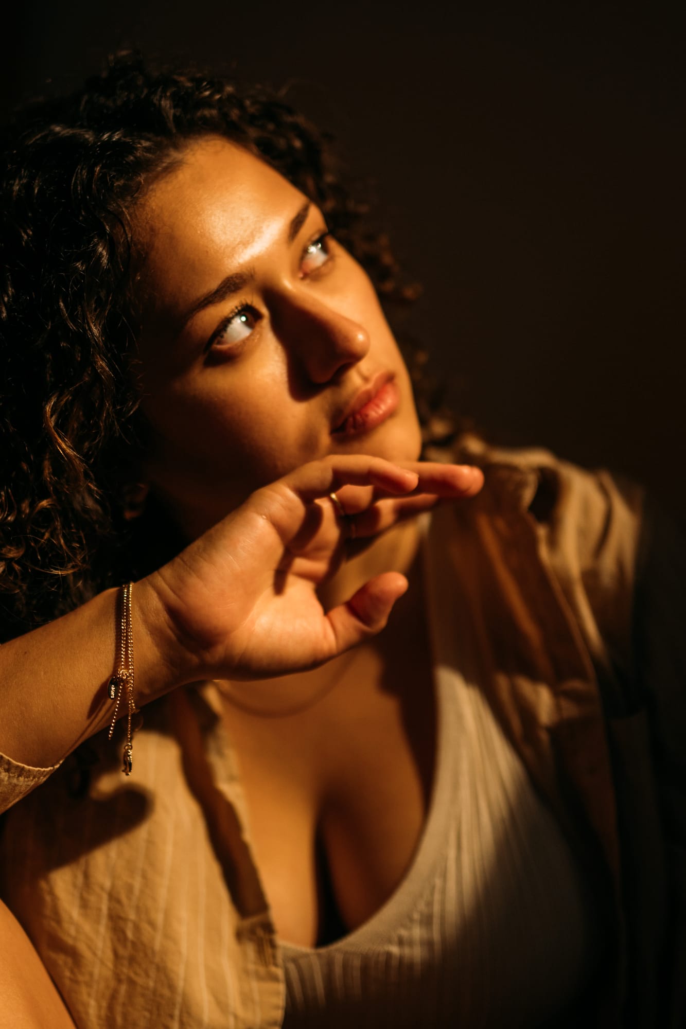 Marina in Warm Window Light portraits story frame 10: Marina in warm indoor light, with amber shadow, denim, black robe, green styling and an intimate editorial portrait mood.