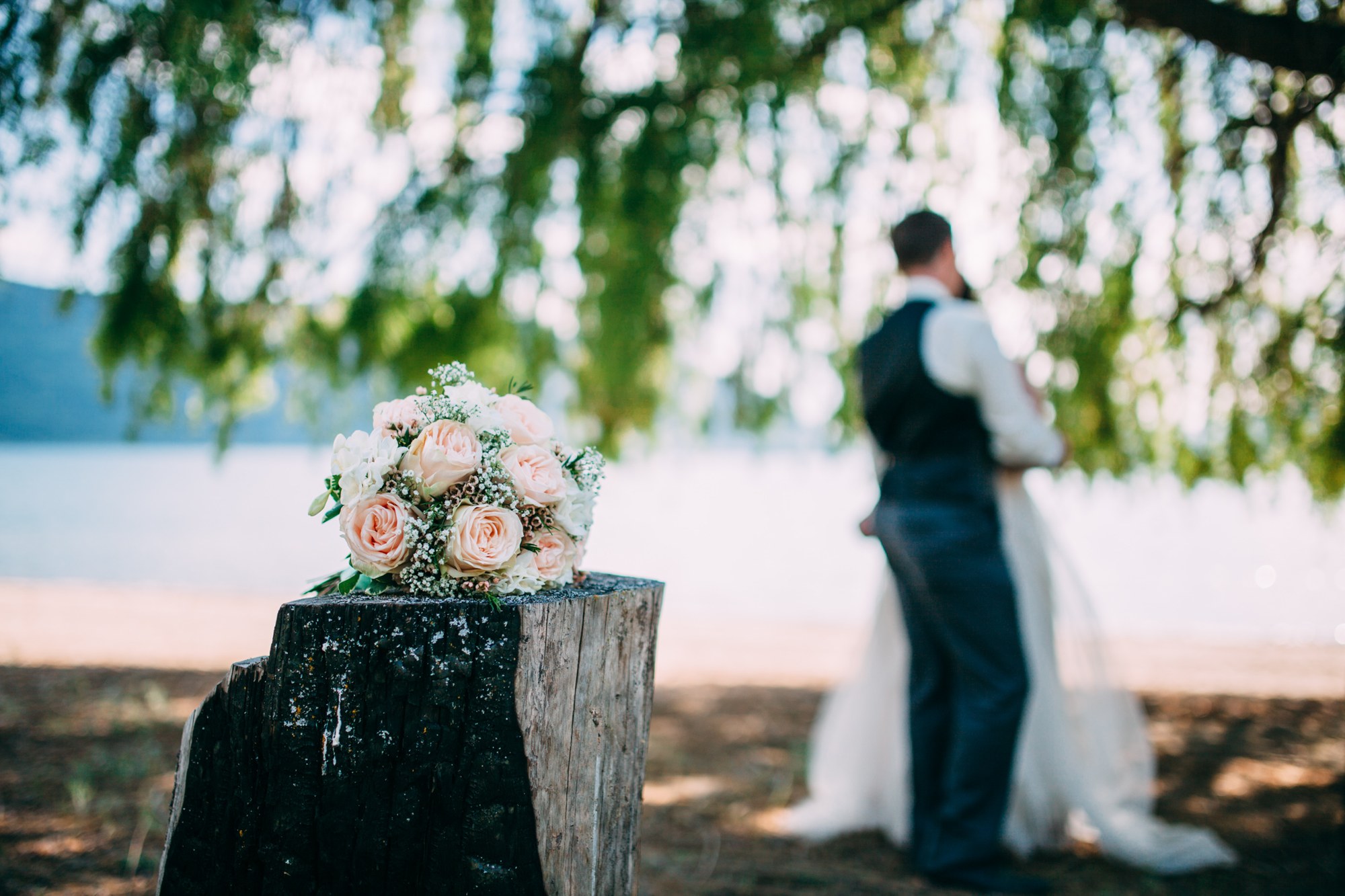Mel & Eric: Bouquet detail with the couple softly framed beyond.