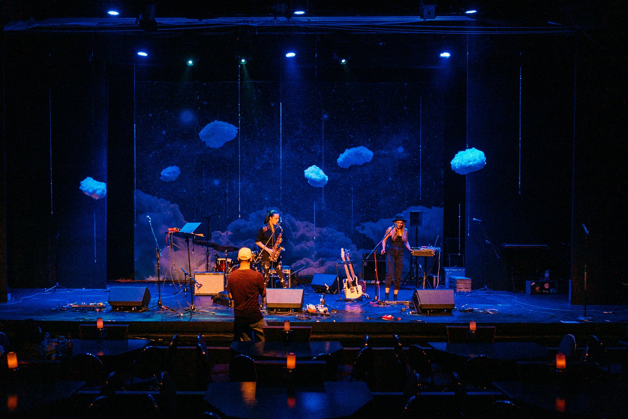 Wider theatre view with MusicBC performers and blue stage lighting.