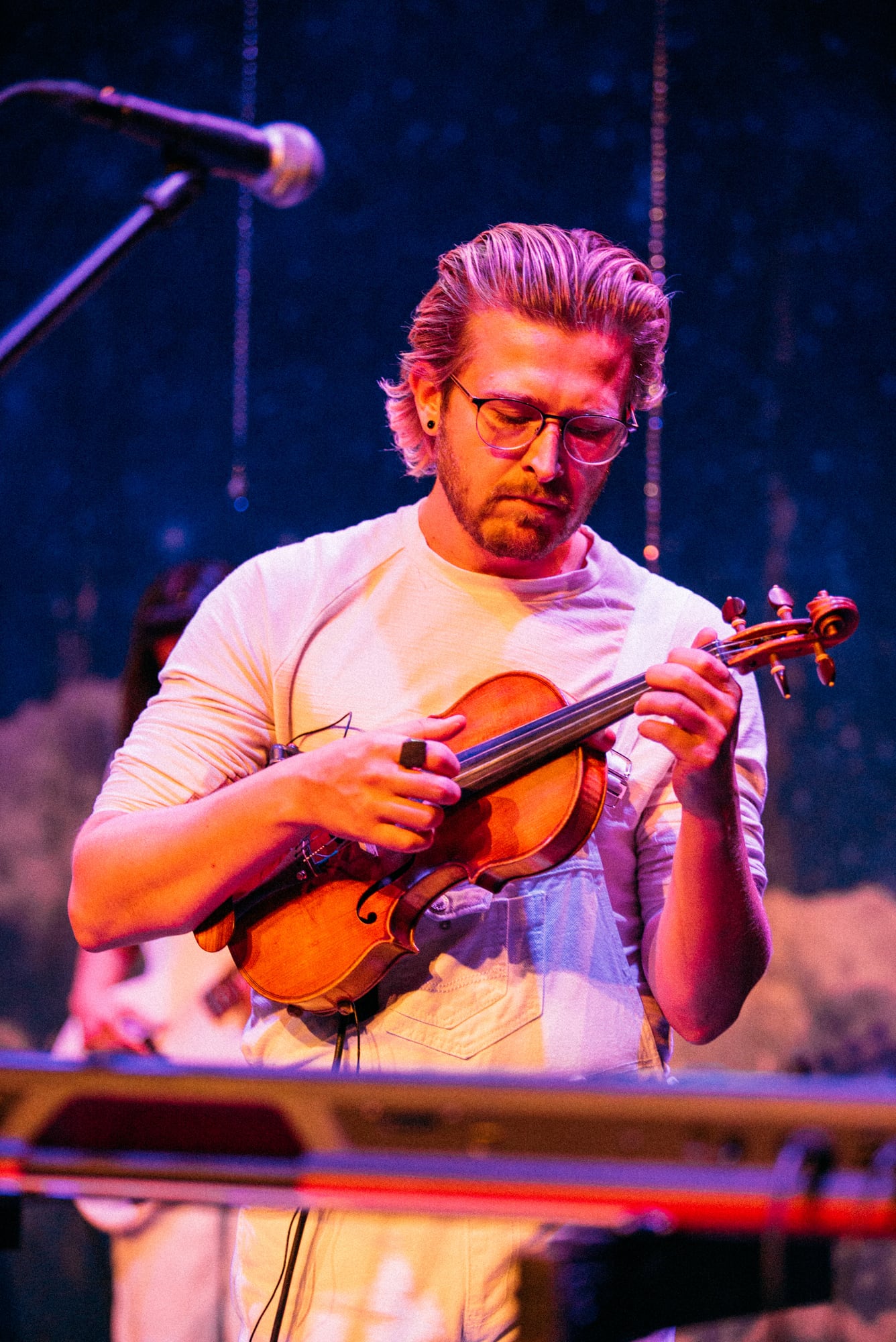 Violin player framed against a dark stage background.