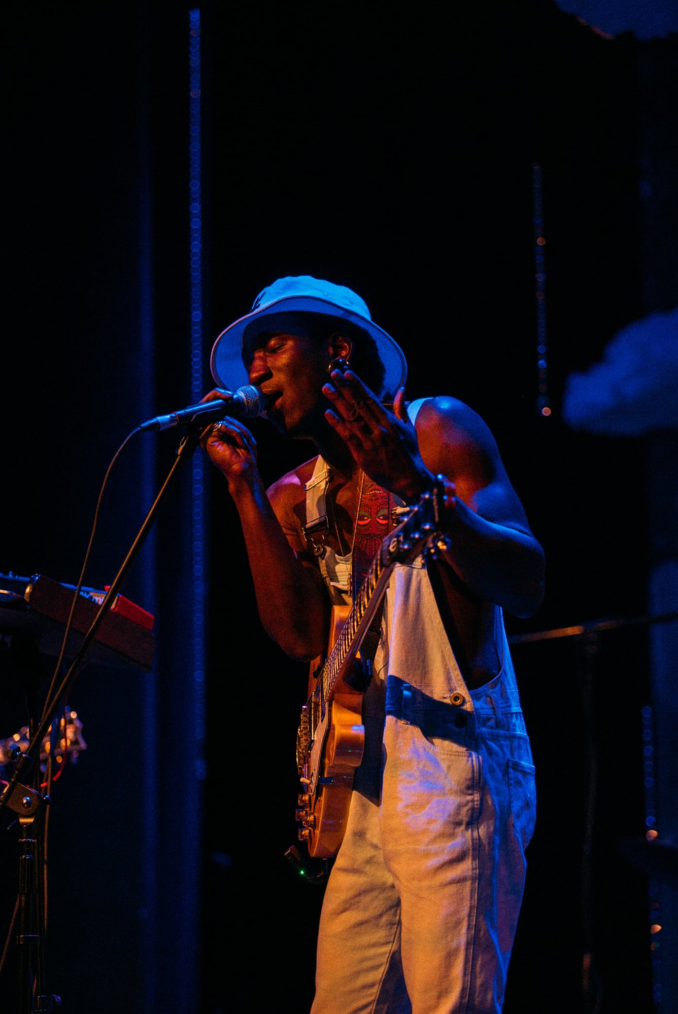Full-length singer-guitarist at microphone against a dark stage.