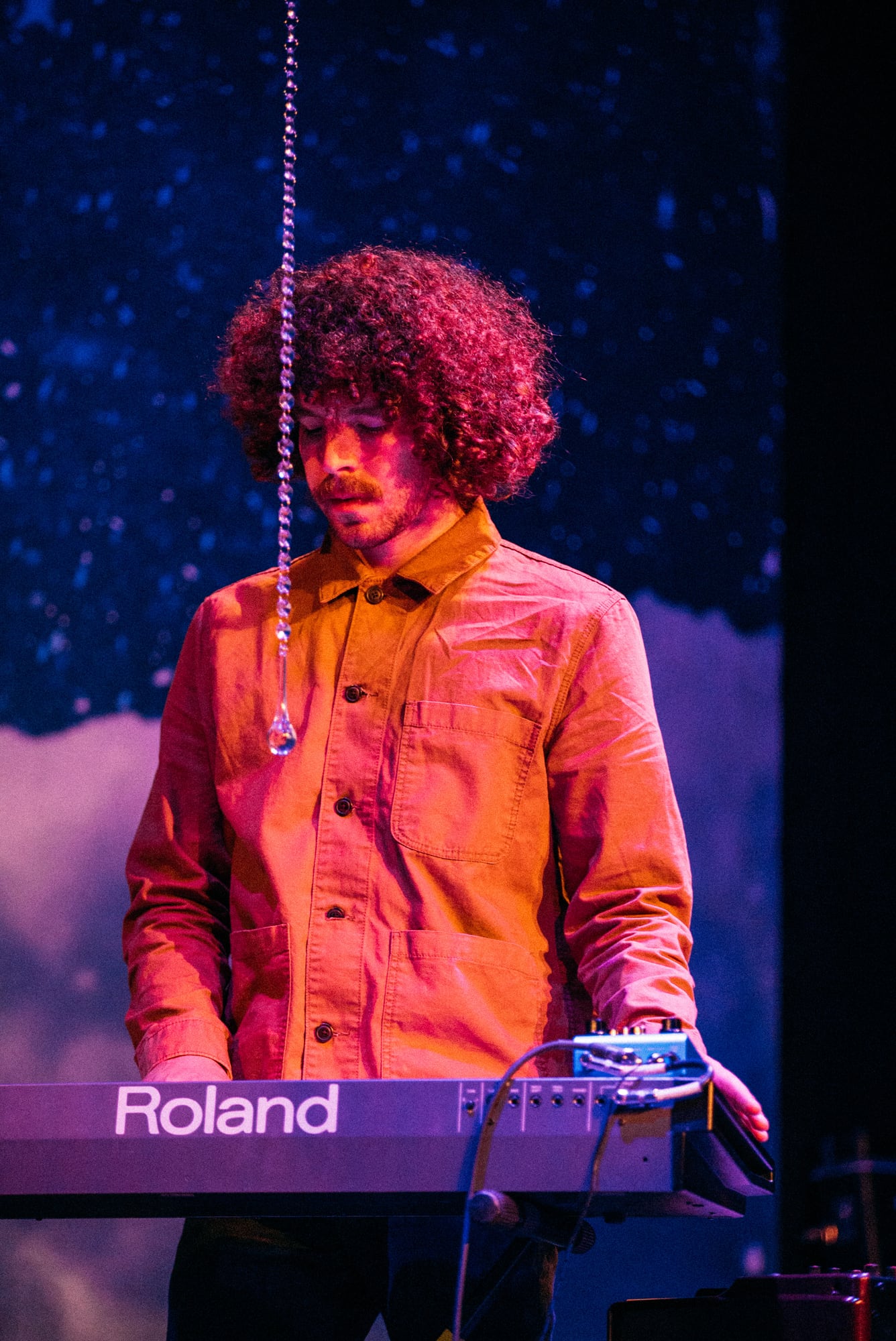 Keyboard player portrait under blue stage light.