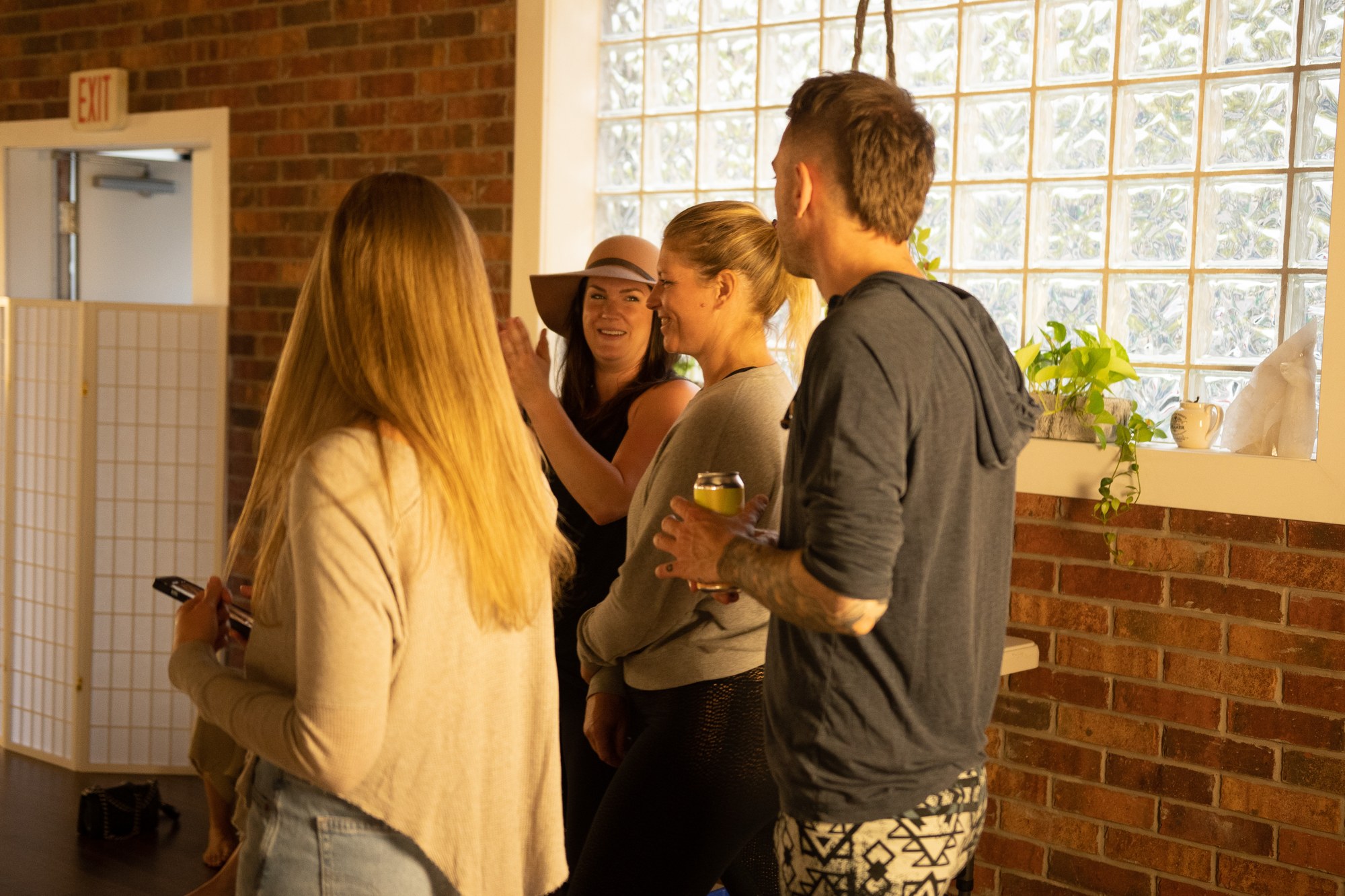 Our Yoga Space Turns Three: Guests chatting beside the brick wall.