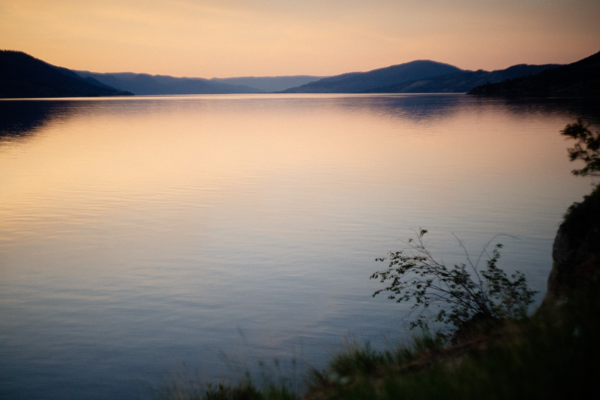 A peach dusk sky reflected in the still water of Okanagan Lake.