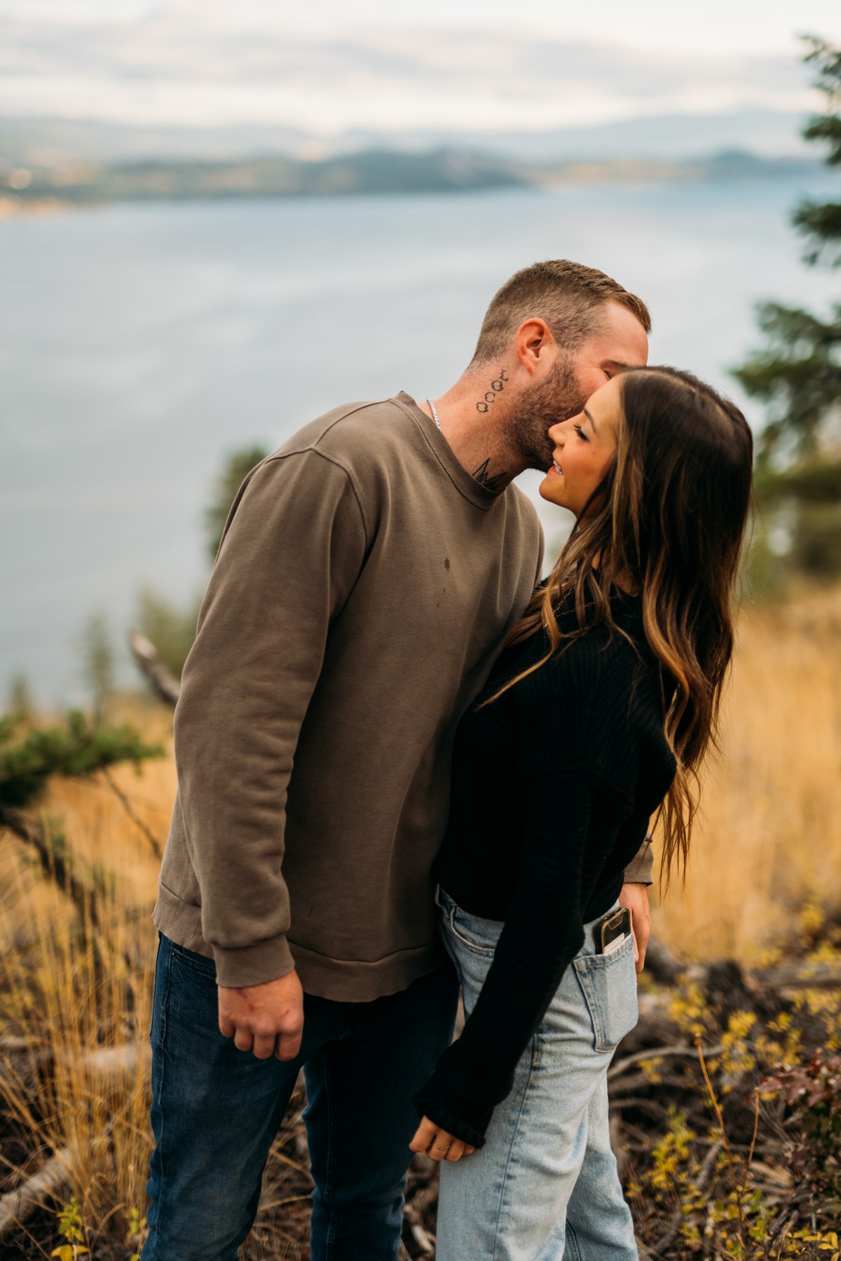 Rachel and Ryan portraits story frame 2: Okanagan couples portraits with dirt bikes, lake and mountain views, autumn sun, standing portraits and champagne celebration.